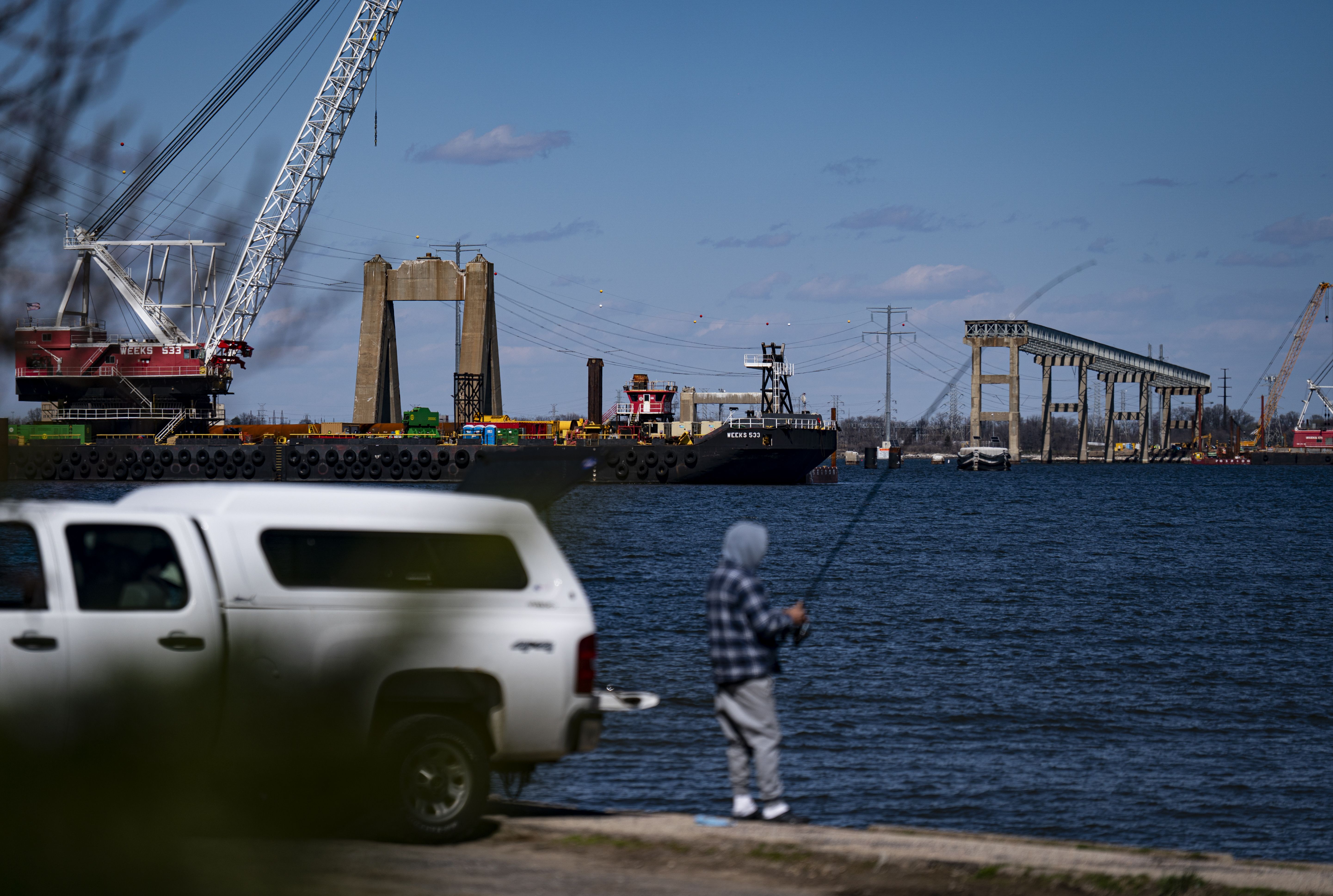 A man fishes in Baltimore, Md., in March near the remnants of the Francis Scott Key Bridge. Photo: Al Drago/Getty Images