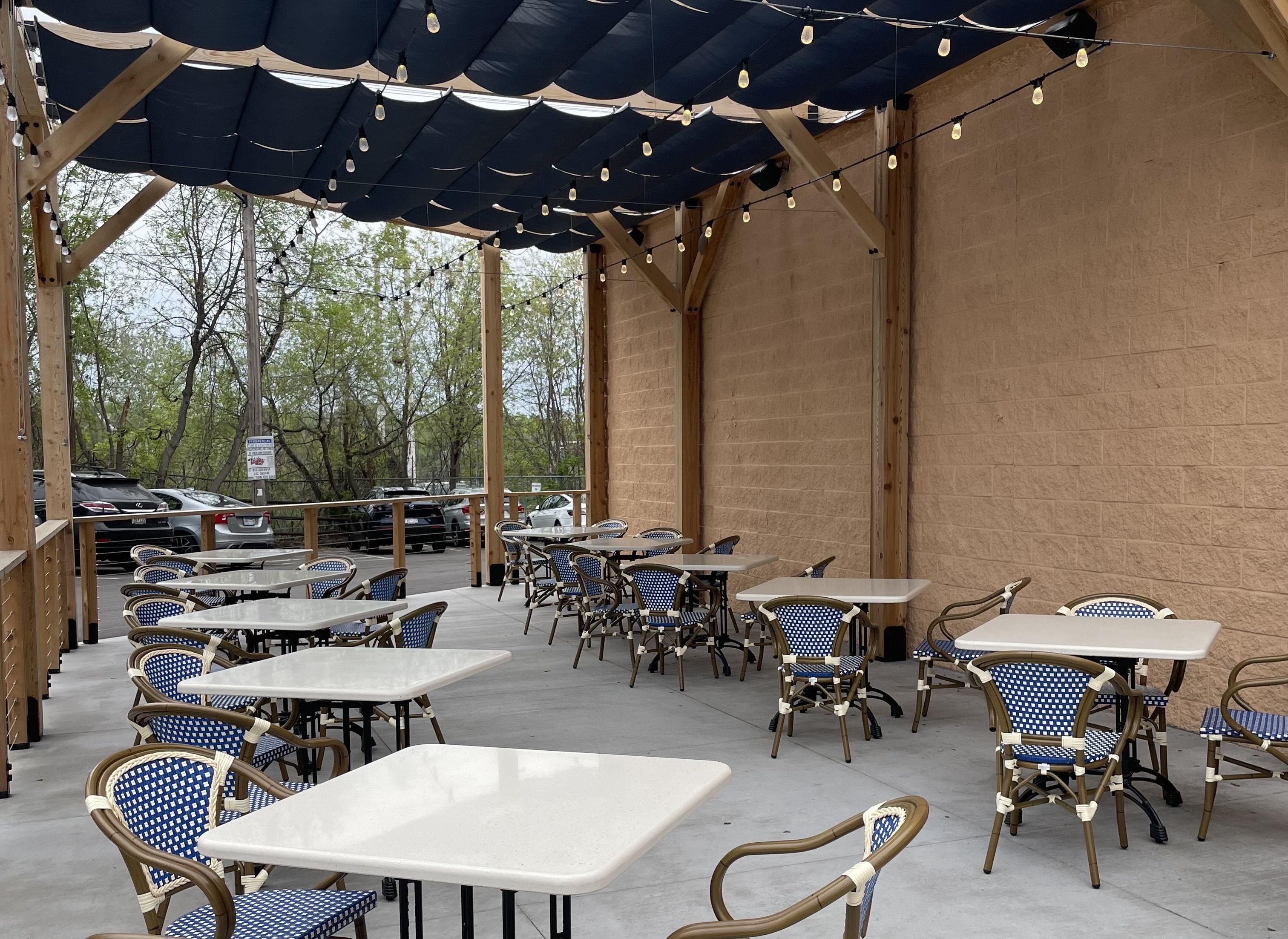 A patio with white tables and blue and white chairs.