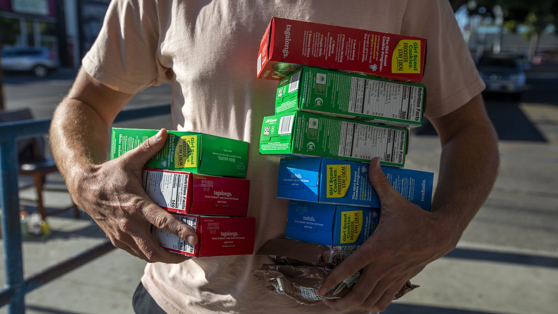 A man holding many boxes of Girl Scout cookies. 