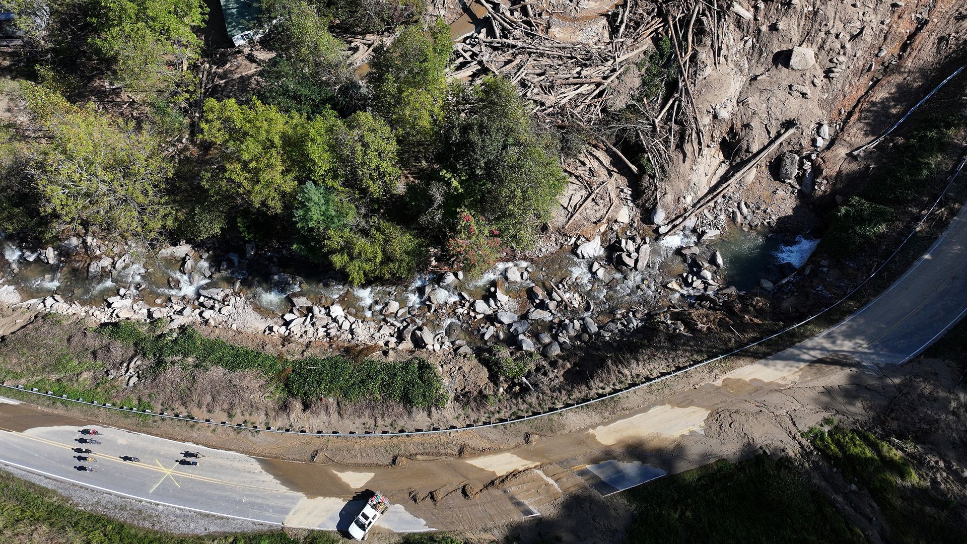  An aerial view of volunteers (LOWER L) making their way on foot past a mudslide caused by flooding wrought by Hurricane Helene, on their way to deliver supplies to residents, on October 3, 2024 near Bat Cave, North Carolina.