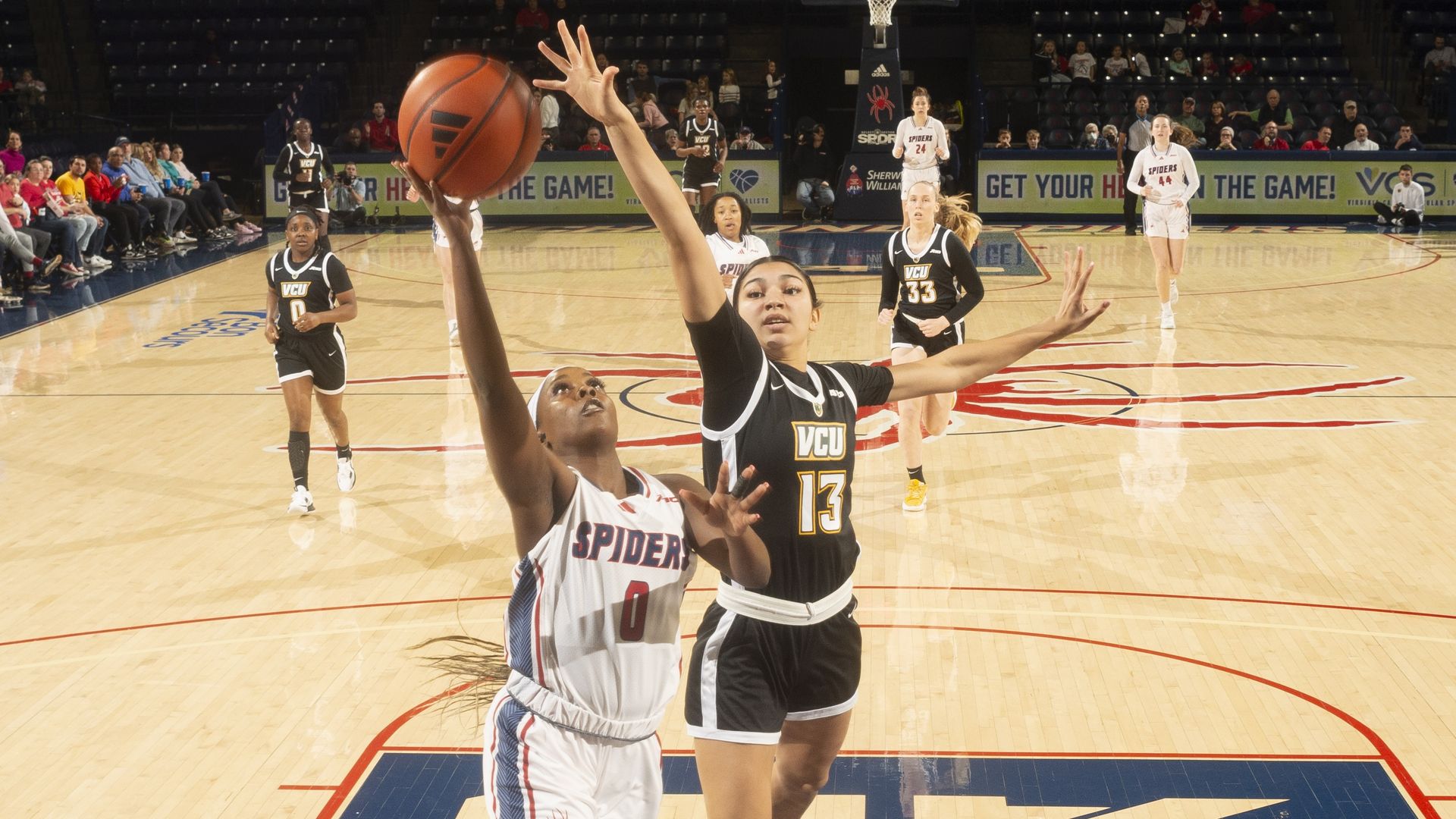 Two woman play basketball and jump for the hoop 