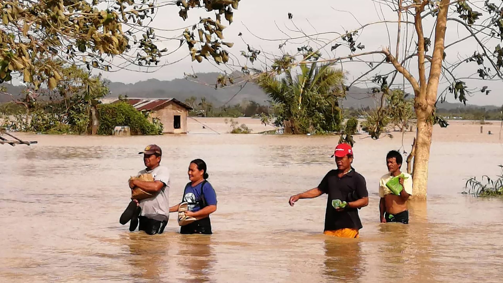 Residents wade through a flooded highway, caused by heavy rains due to typhoon Phanfone, in Ormoc City, Leyte province in central Philippines on December 25, 2019.