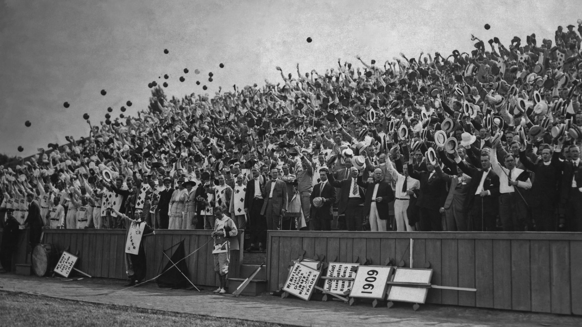 A black and white photo of graduates throwing their caps into the air