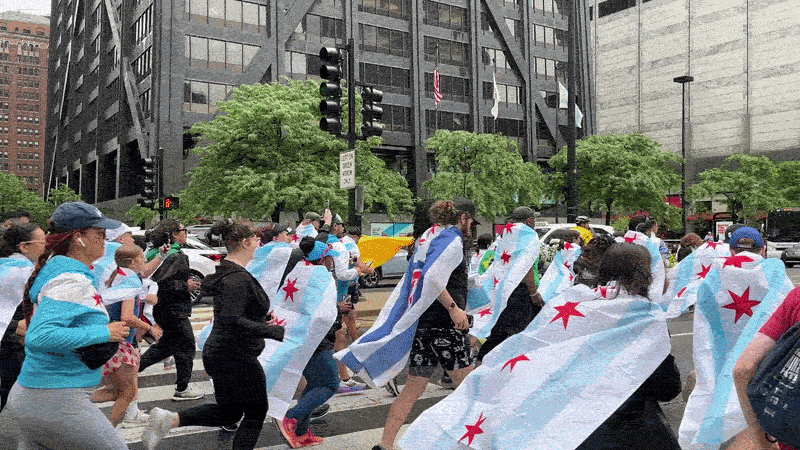 A gif of people running on Michigan Avenue with Chicago flags on their backs.