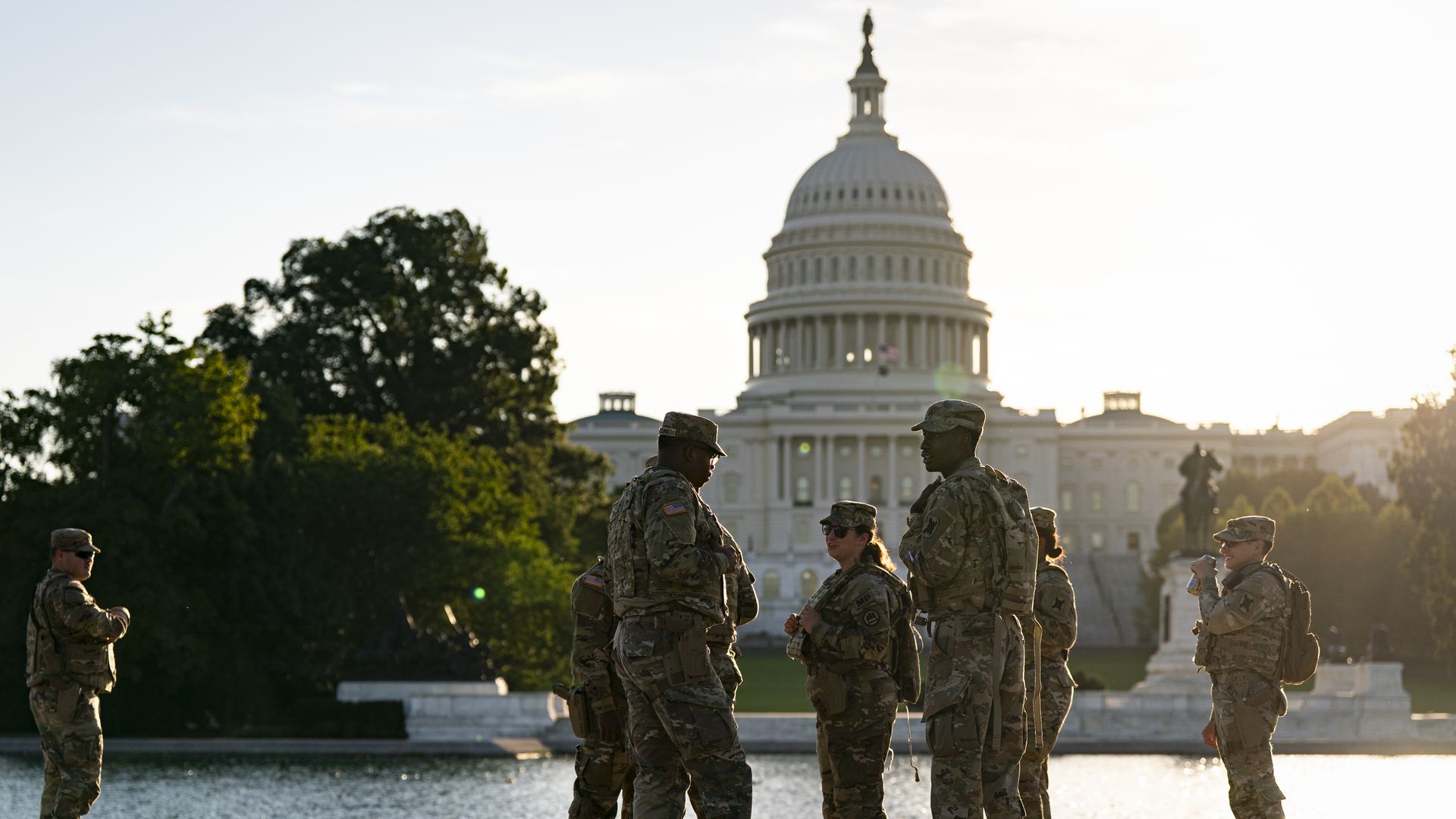 Several members of the National Guard stand in front of the U.S. Capitol in uniform. 