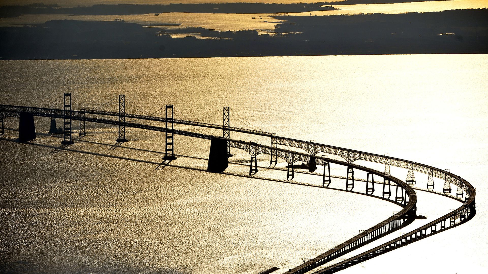 The Bay Bridge at sunset with golden water surrounding it.