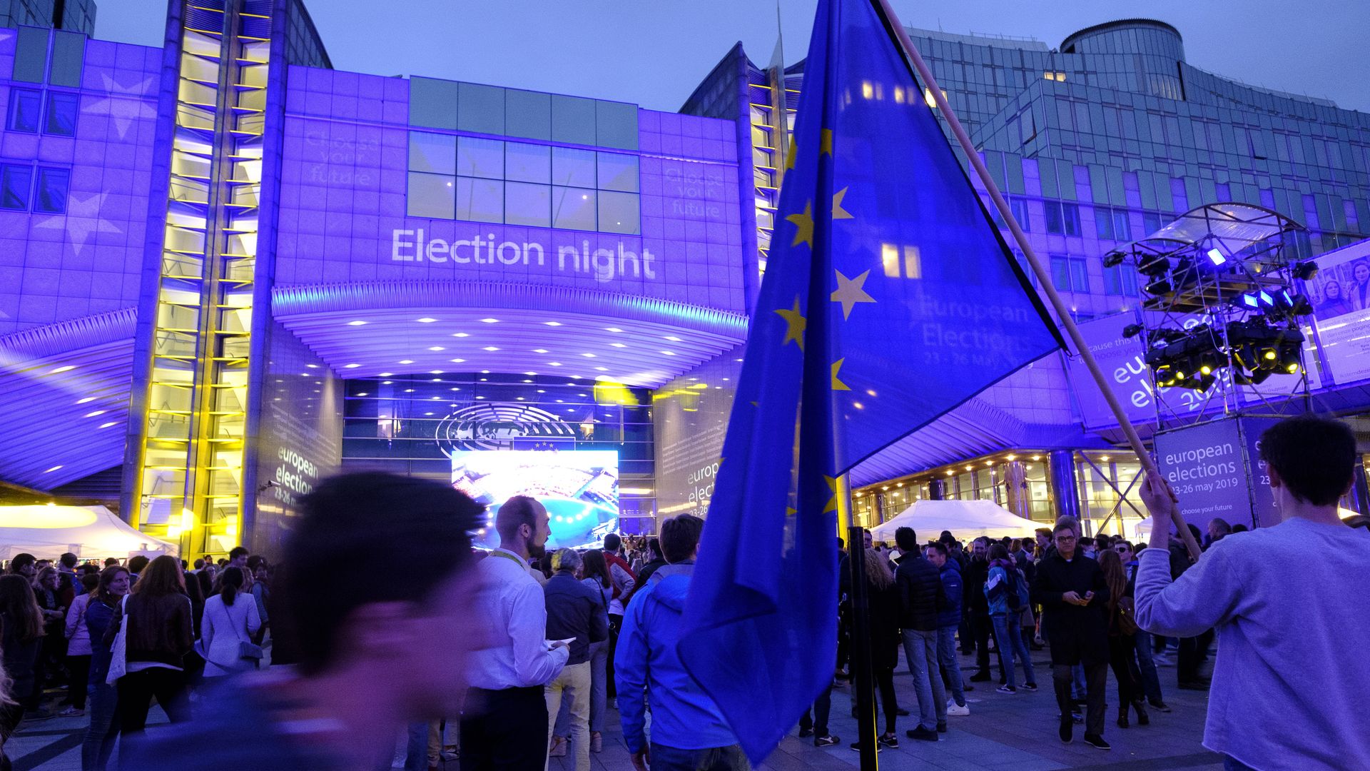 EU citizens are seen outside the European Parliament building at dusk in Brussels. 