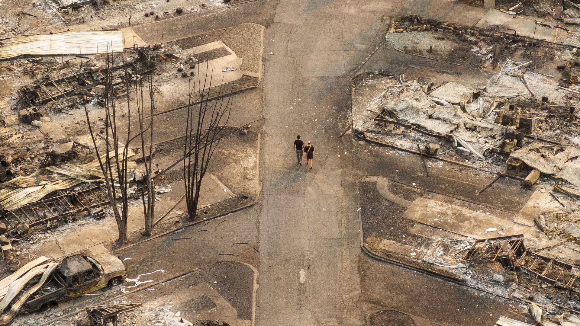 Drone's-eye view: Two people hold hands while walking through a mobile home park destroyed by fire Thursday in Phoenix, Ore.
