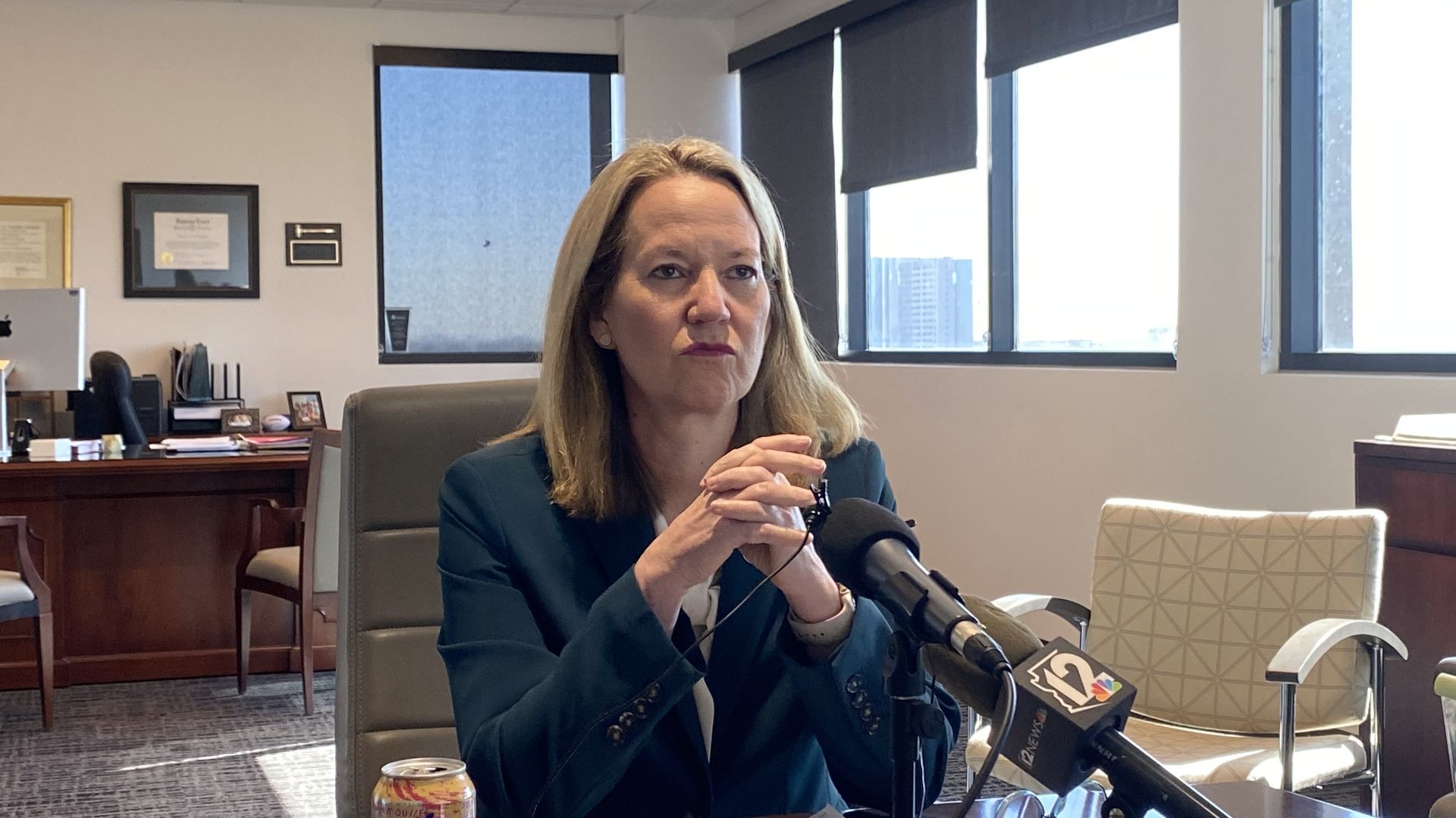Kris Mayes sits at a table with her hands folded in front of her above the table. 