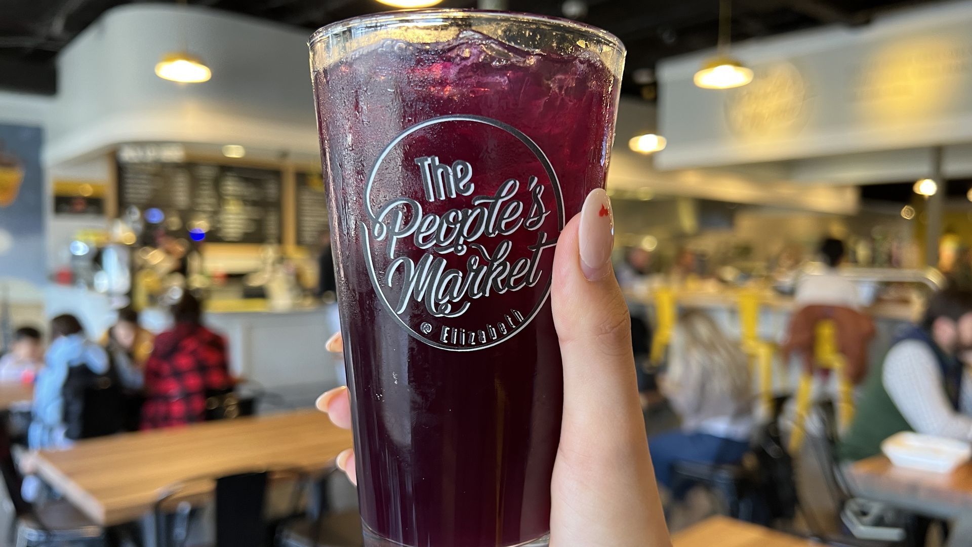 hand holding cup that reads "the people's market"