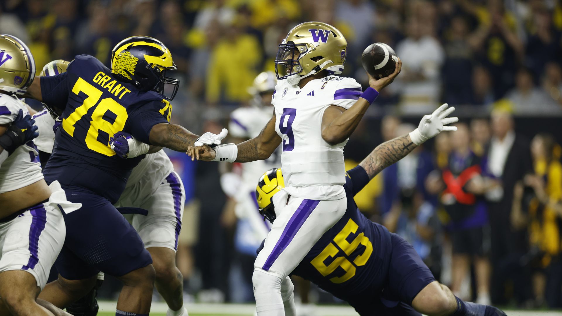 Michael Penix Jr, the Huskies' quarterback, pulls back to throw while surrounded by Michigan players.