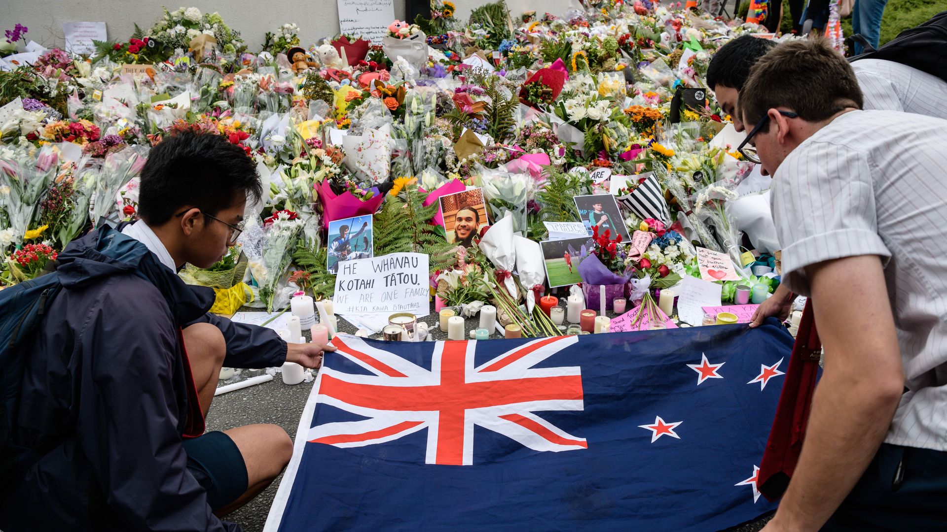 Students display the New Zealand national flag next to flowers during a vigil in Christchurch on March 18, 2019