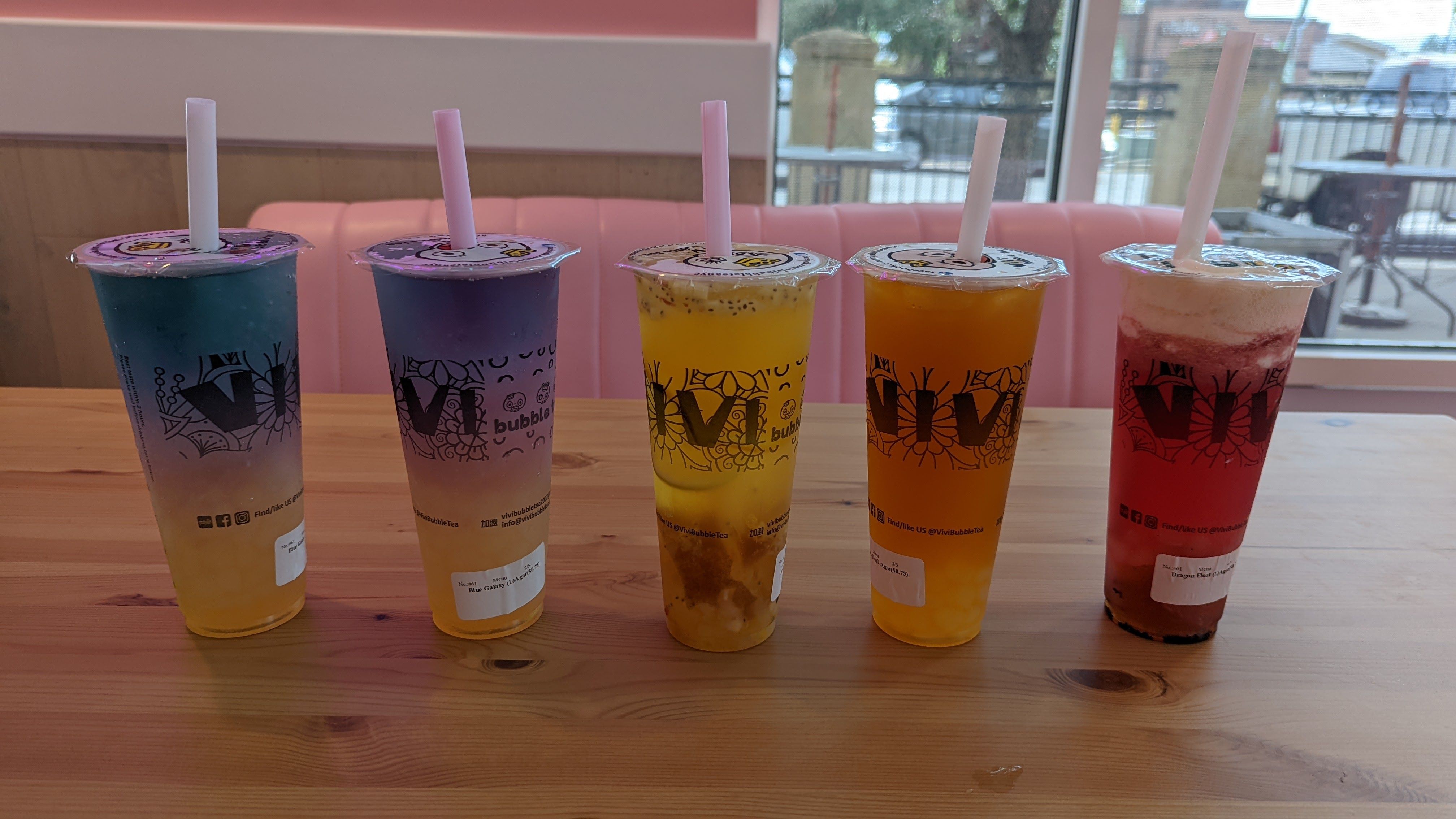 Five cups of boba tea sit on a table.