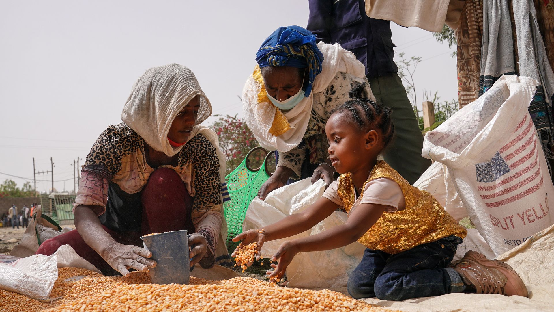 An aid worker distributes measured portions of yellow lentils to residents of Geha subcity at an aid operation run by USAID, Catholic Relief Services and the Relief Society of Tigray on June 16, 2021