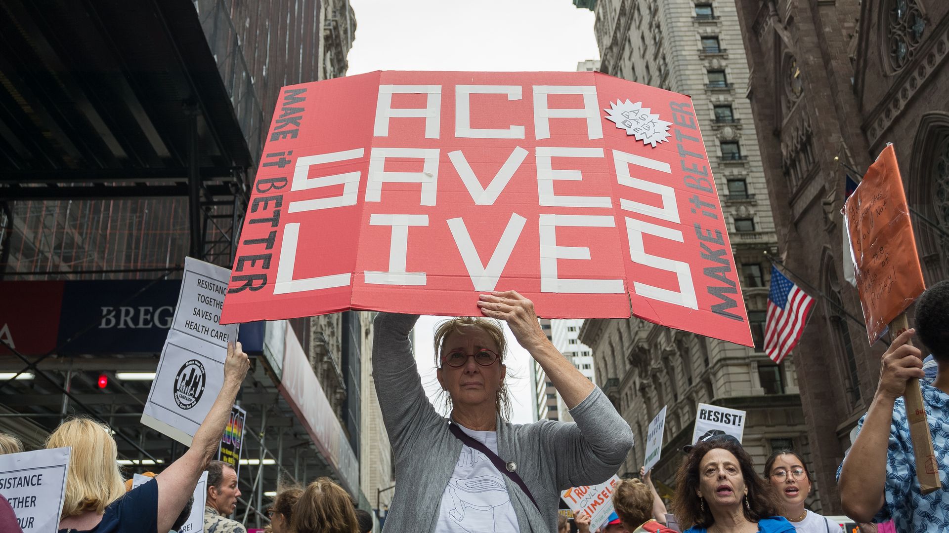 A protester in New York holds a sign saying, "ACA saves lives"