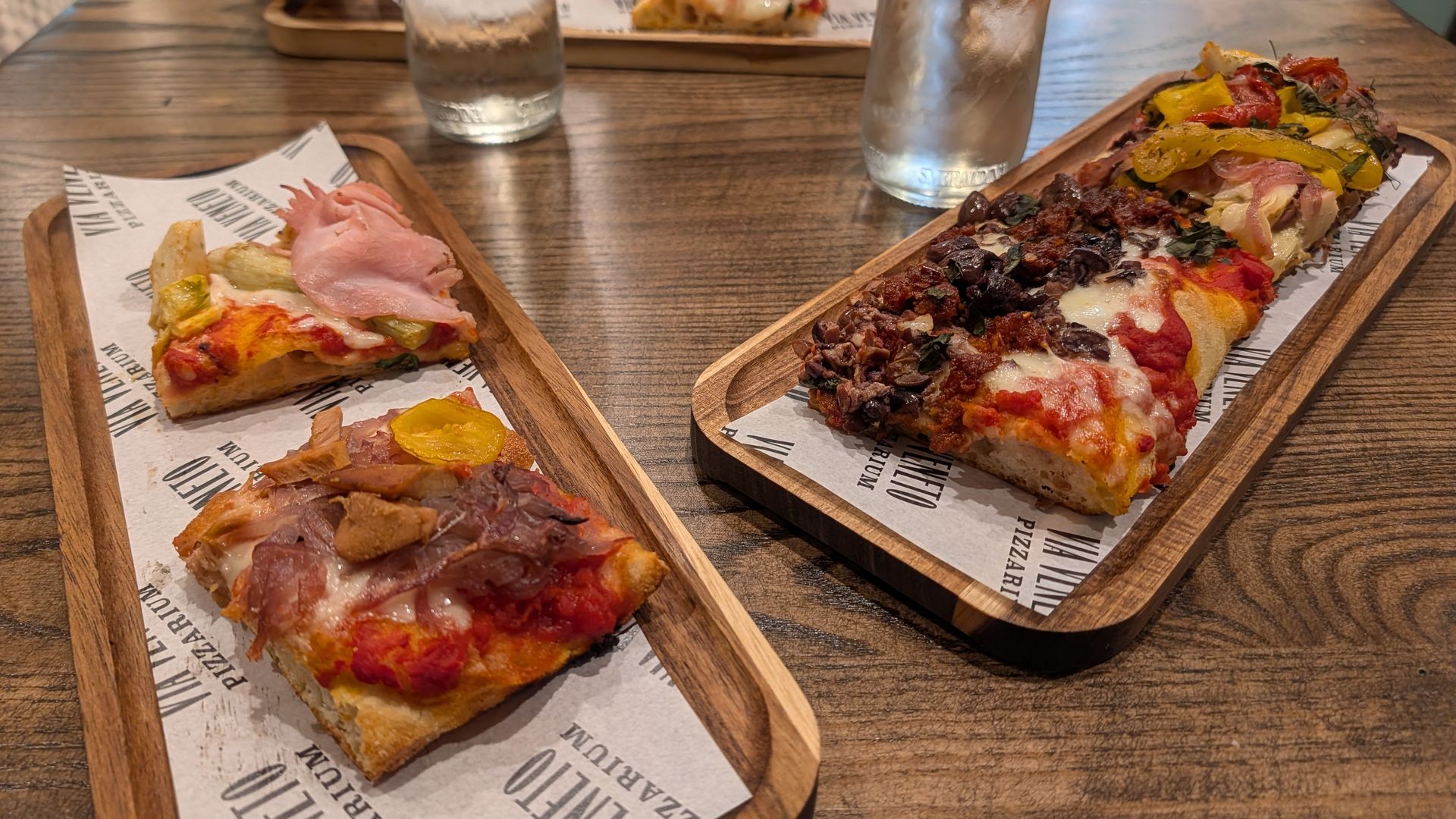 Square slices of Roman-style pizza on wooden plates.