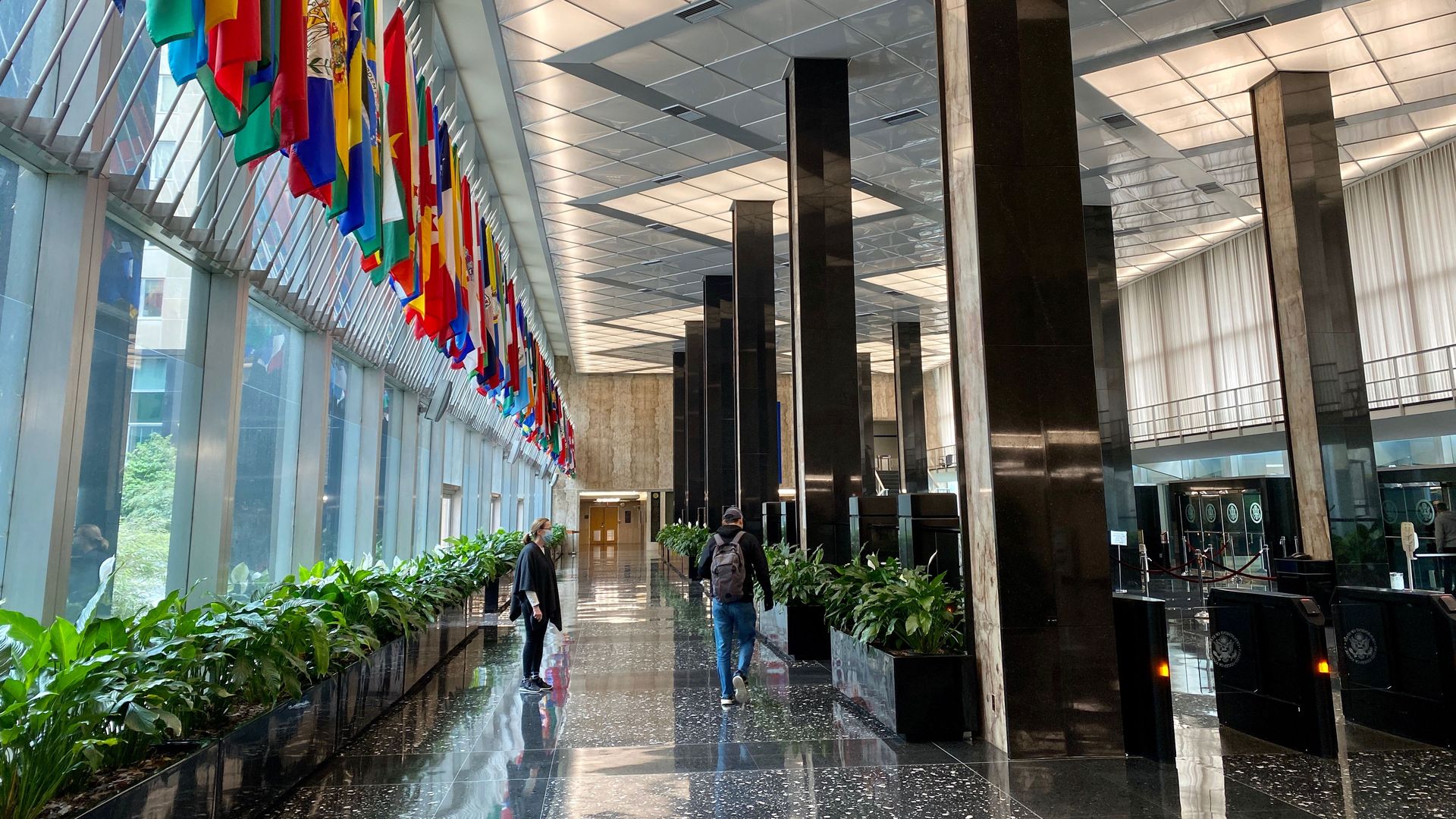 Photo of the interior of the State Department building, which has a line of flags on the left and an open walkway