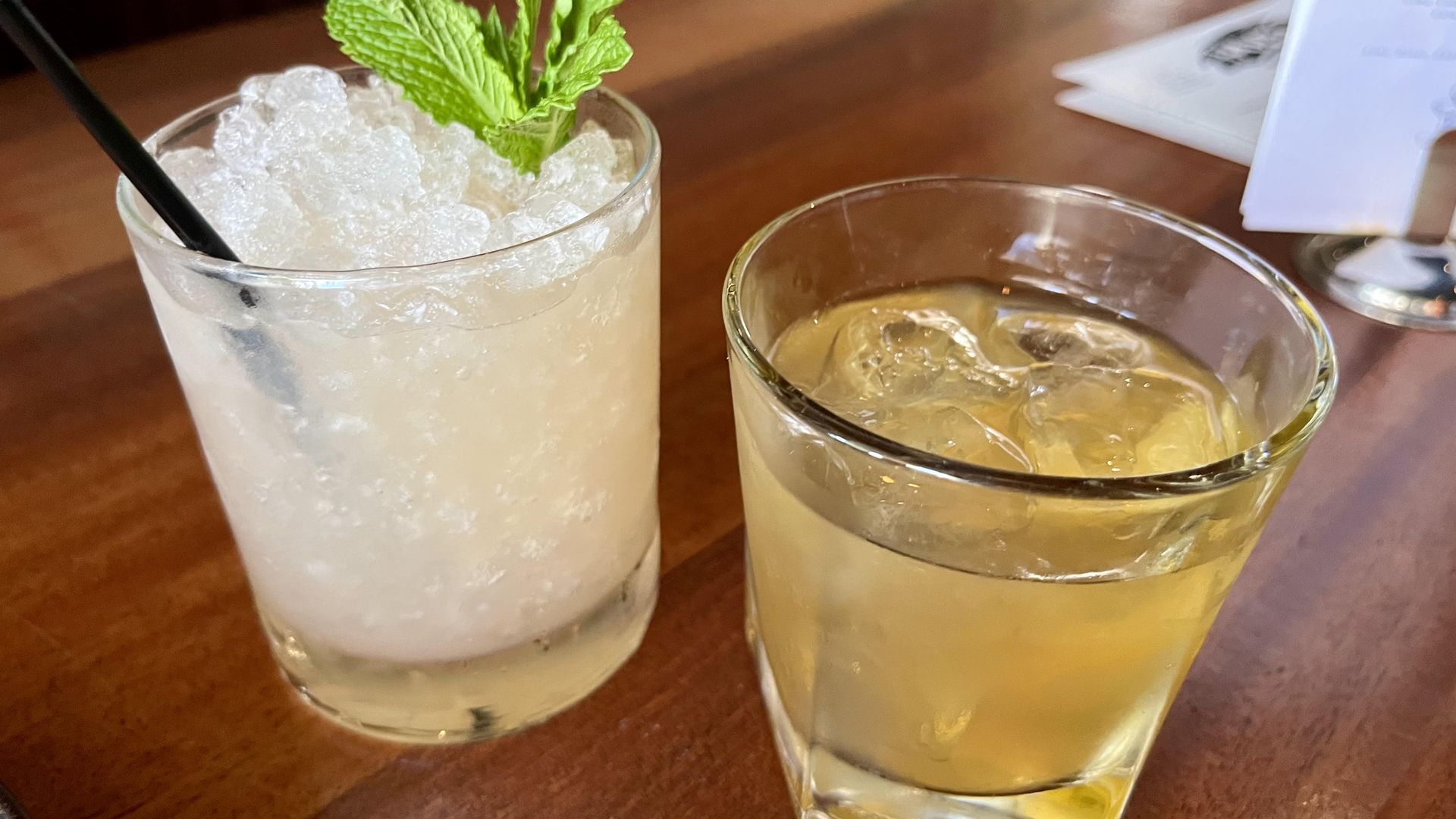 Left is a cocktail with lots of ice and mint. Right is a honey colored cocktail.