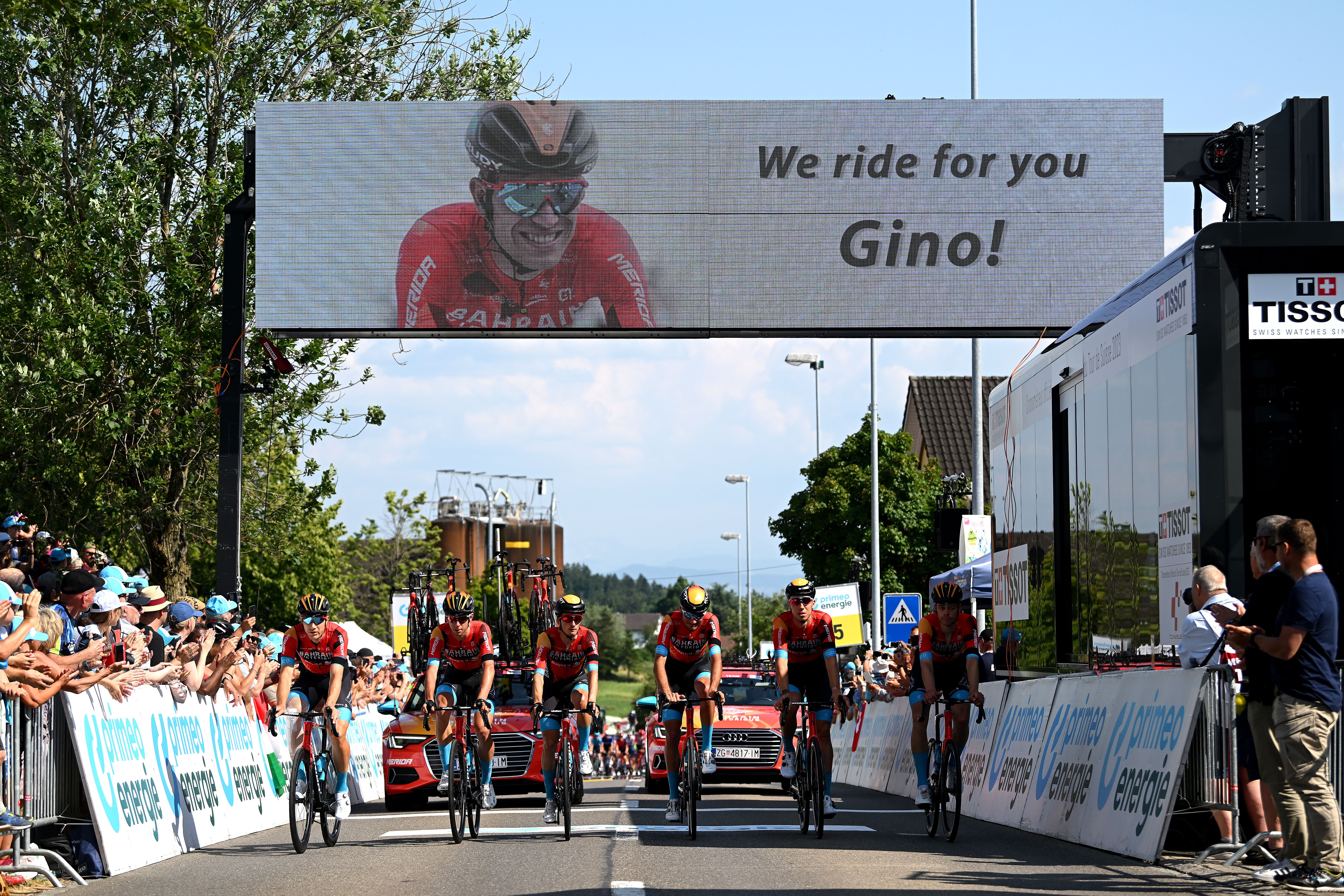 cyclists under sign in tribute to gino