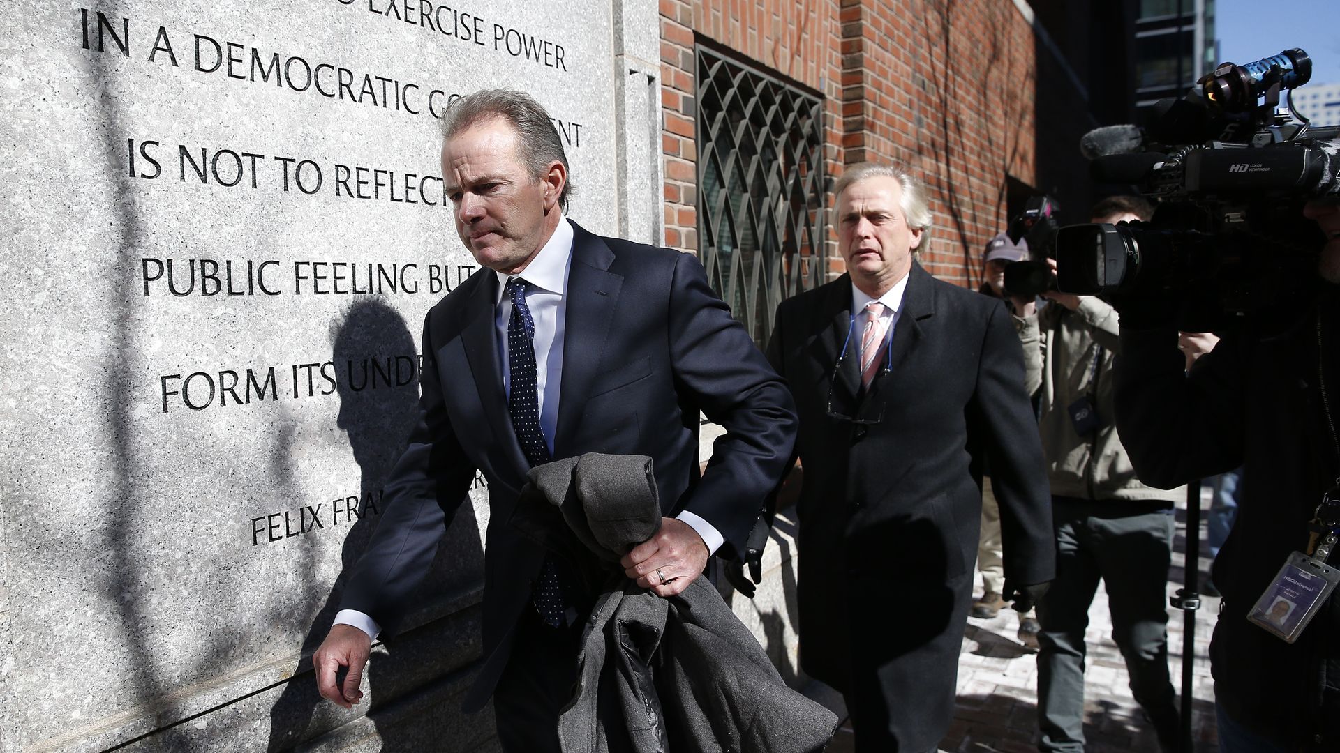 Photo of Gordon Ernst and another person walking outside a red brick courthouse
