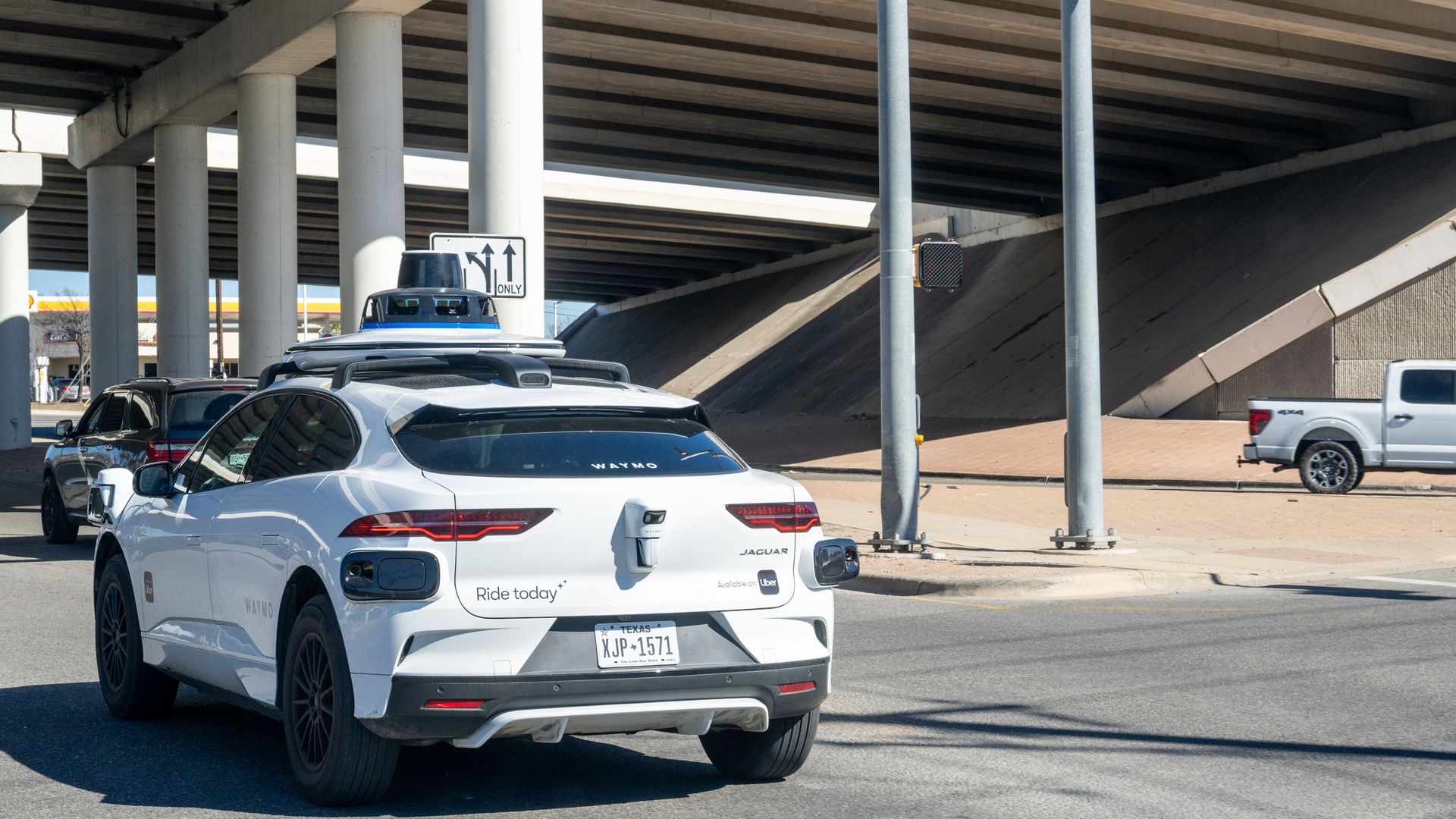 A Waymo is seen in Austin earlier this year entering a road under a highway overpass.