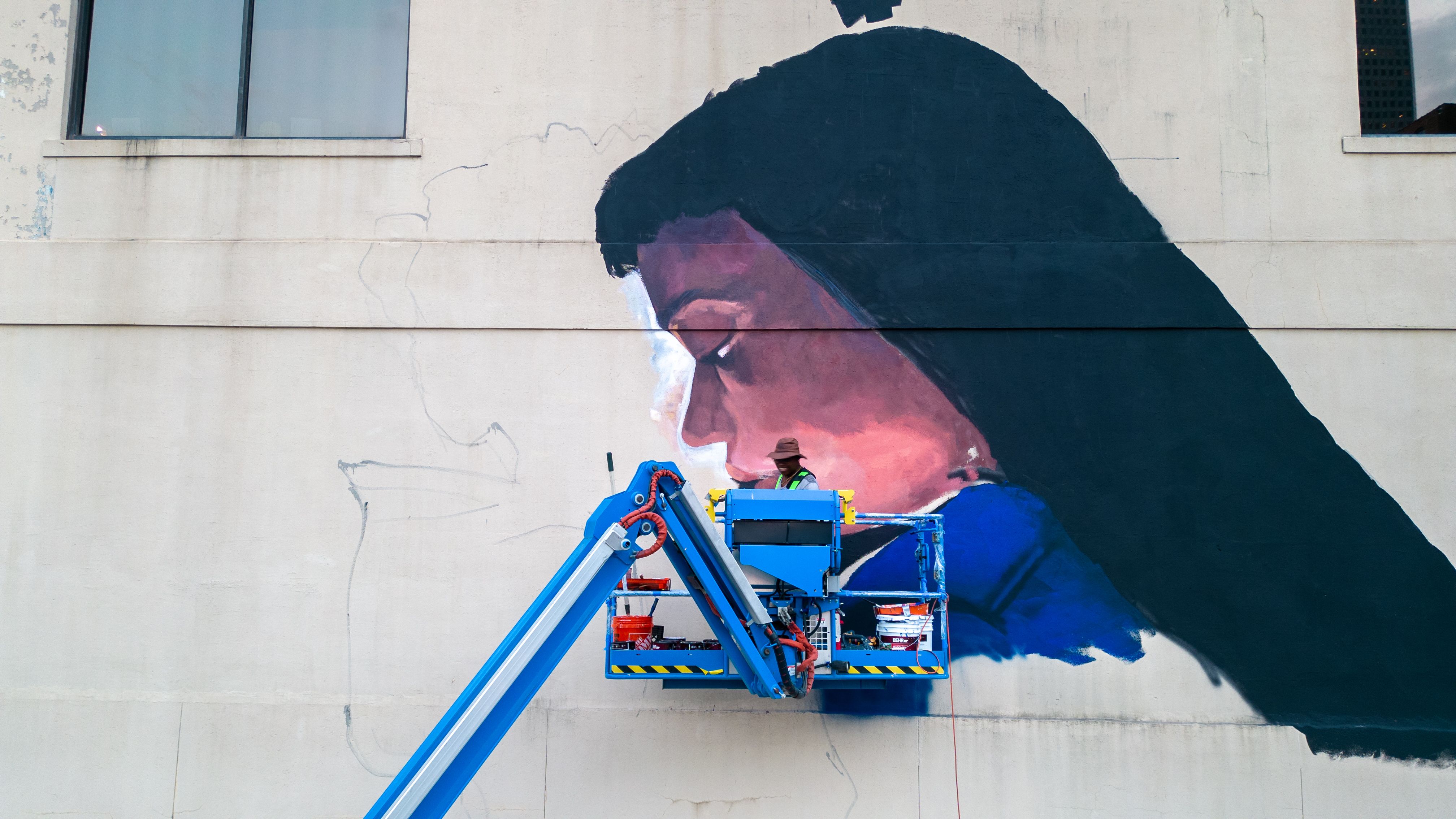 Photo of someone painting a mural of a girls face. 