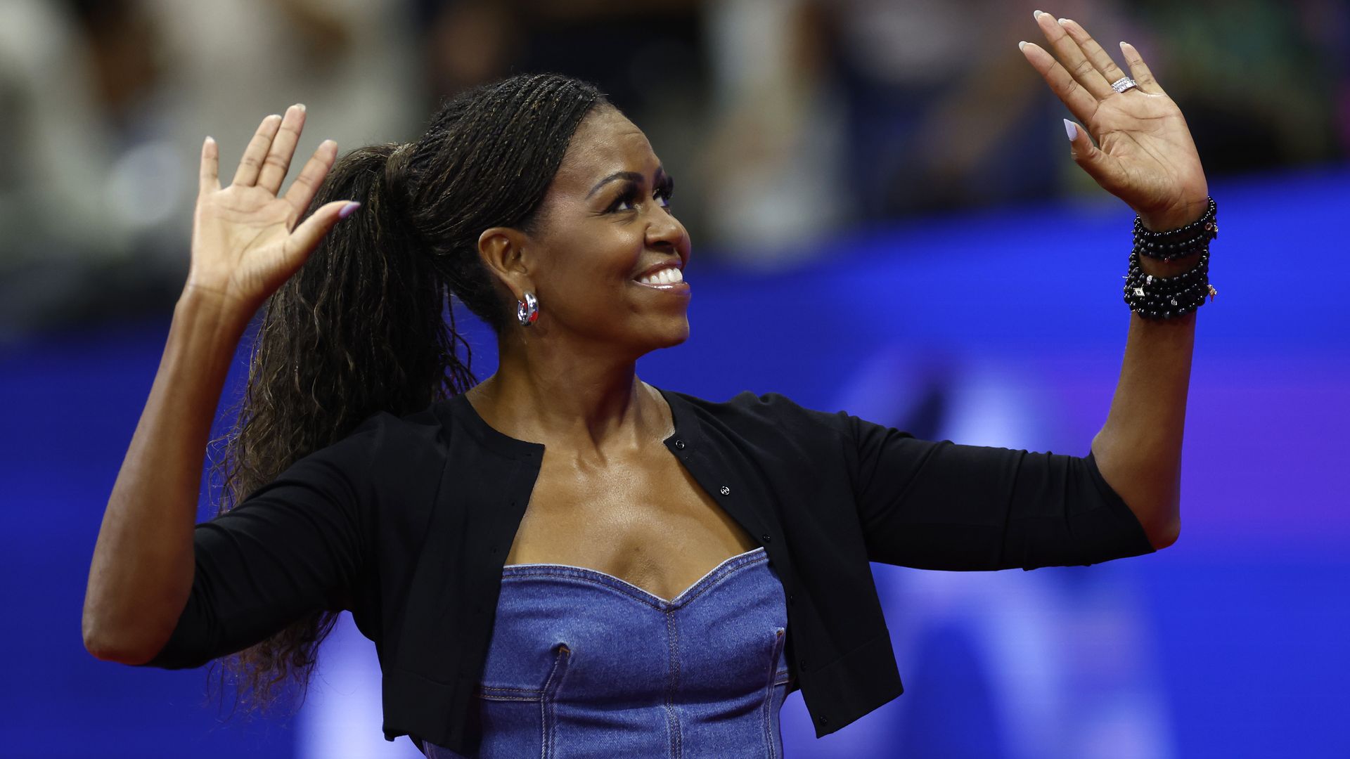 Former first lady of the United States Michelle Obama waves with both hands during a ceremony honoring 50 years of equal pay at the U.S Open at the USTA Billie Jean King National Tennis Center on August 28, 2023 in Queens, New York City.