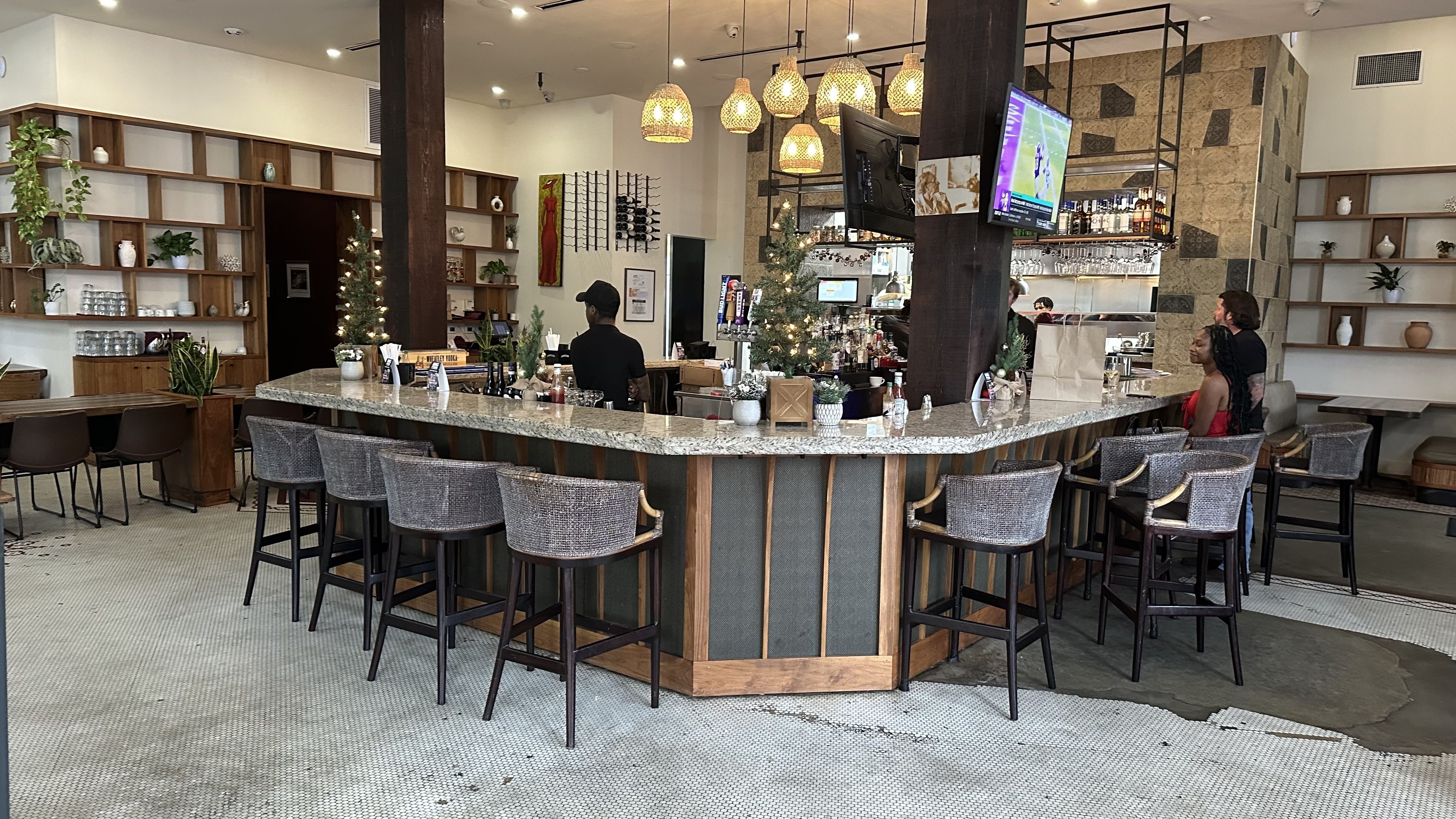 A restaurant interior with bookshelves along the walls and modern bar seating.
