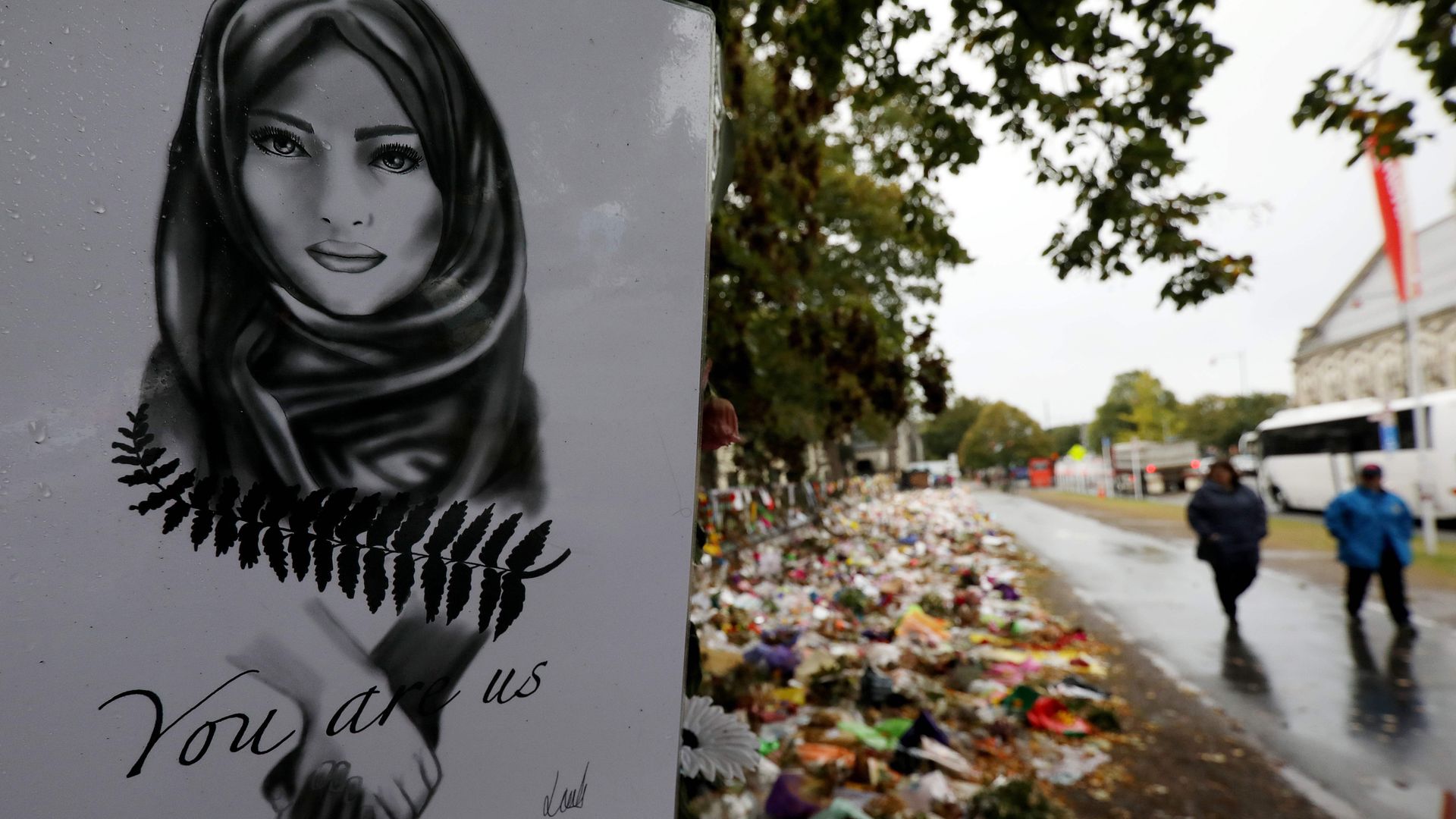 People walk past flowers and tributes displayed in memory of the twin mosque massacre victims