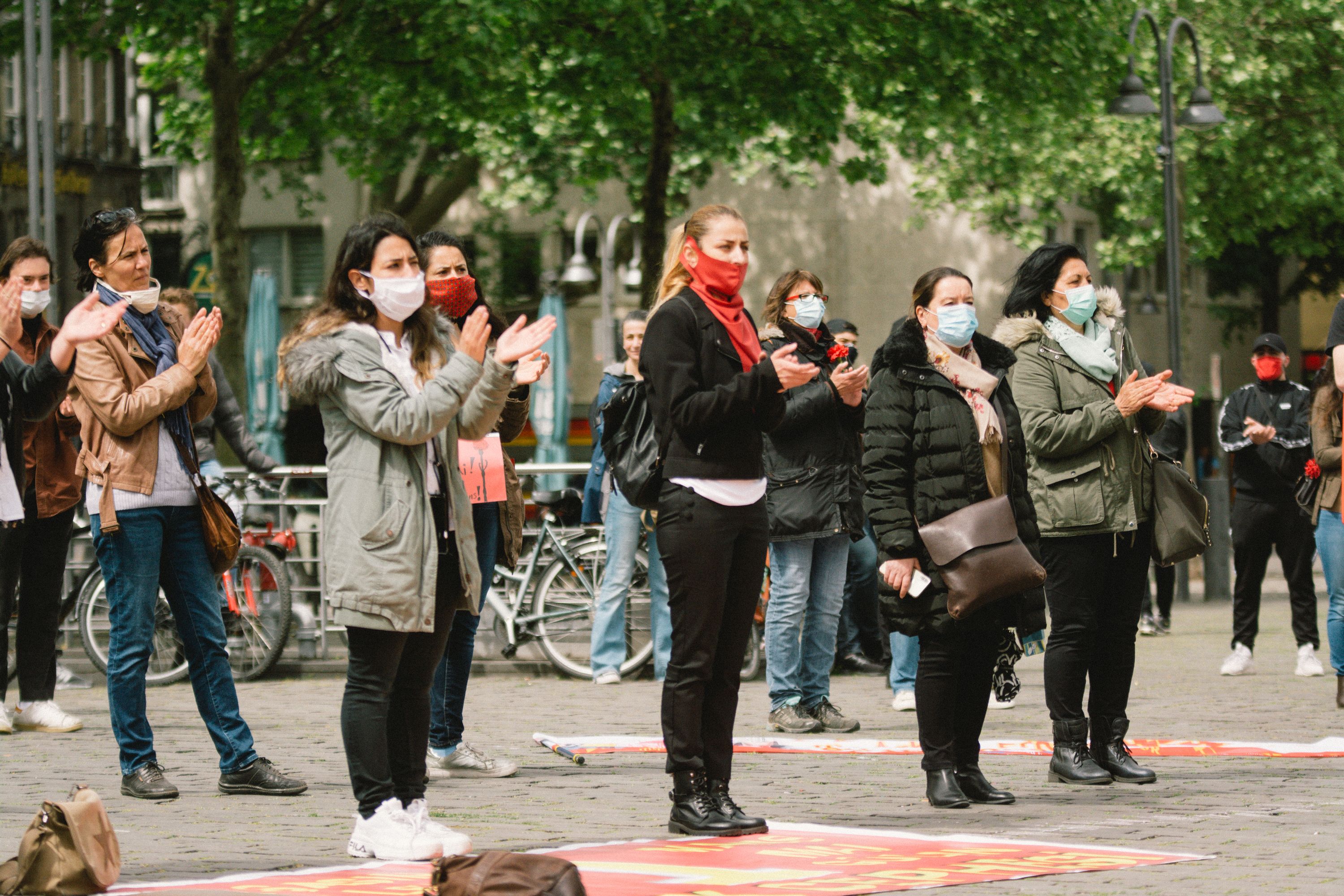 In this image, a line of protestors stand socially distanced while wearing face masks