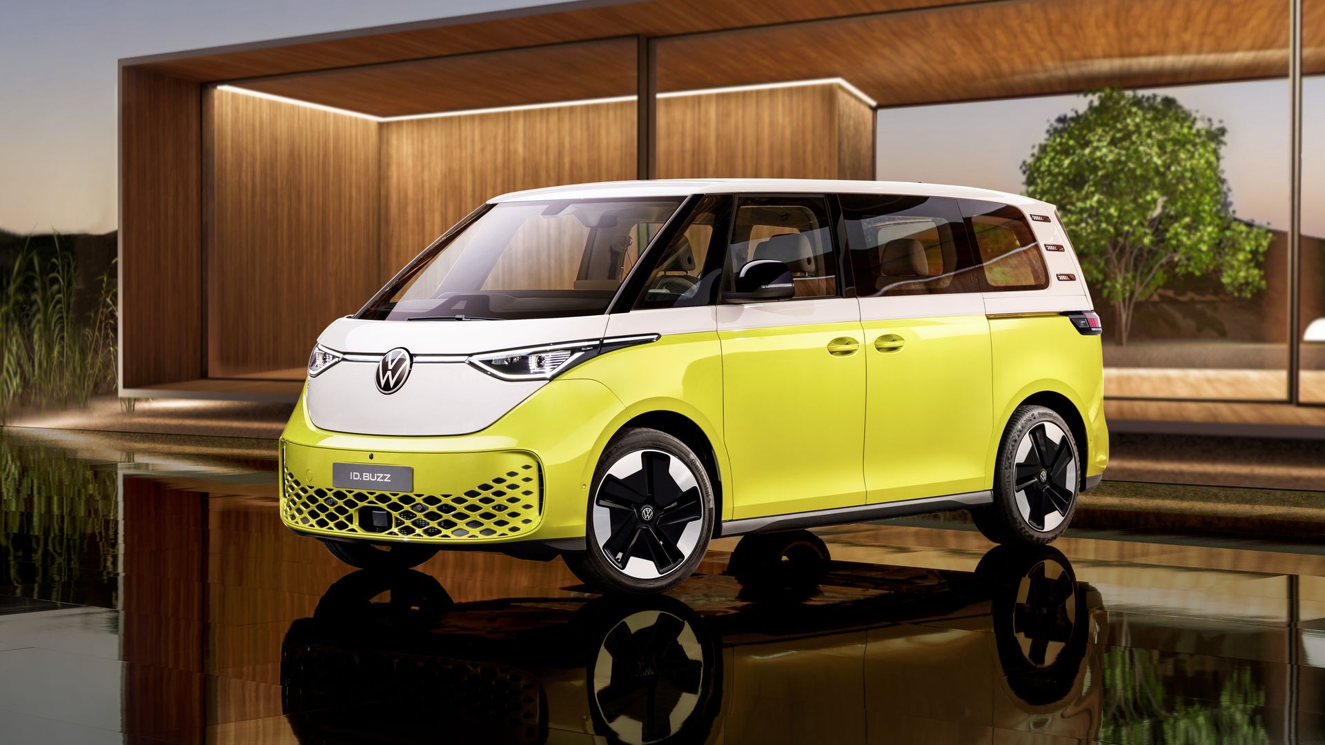 A yellow van with a white roof sits on a shiny floor against a backdrop of a wooden wall.