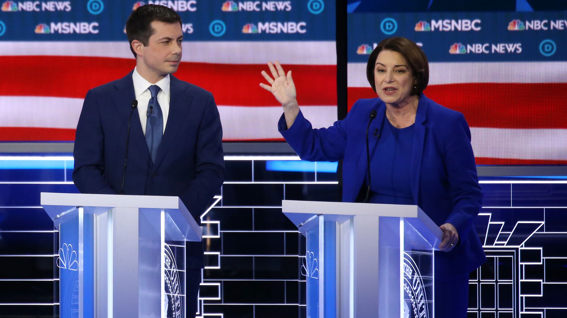 In this image, Klobuchar stands next to Buttigieg on stage