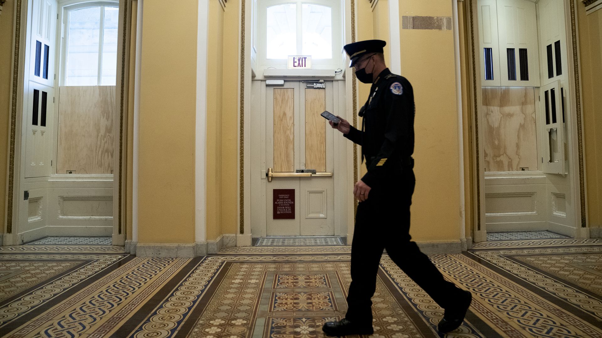 A Capitol Police officer is seen walking past boarded-up windows as he walks through the building.