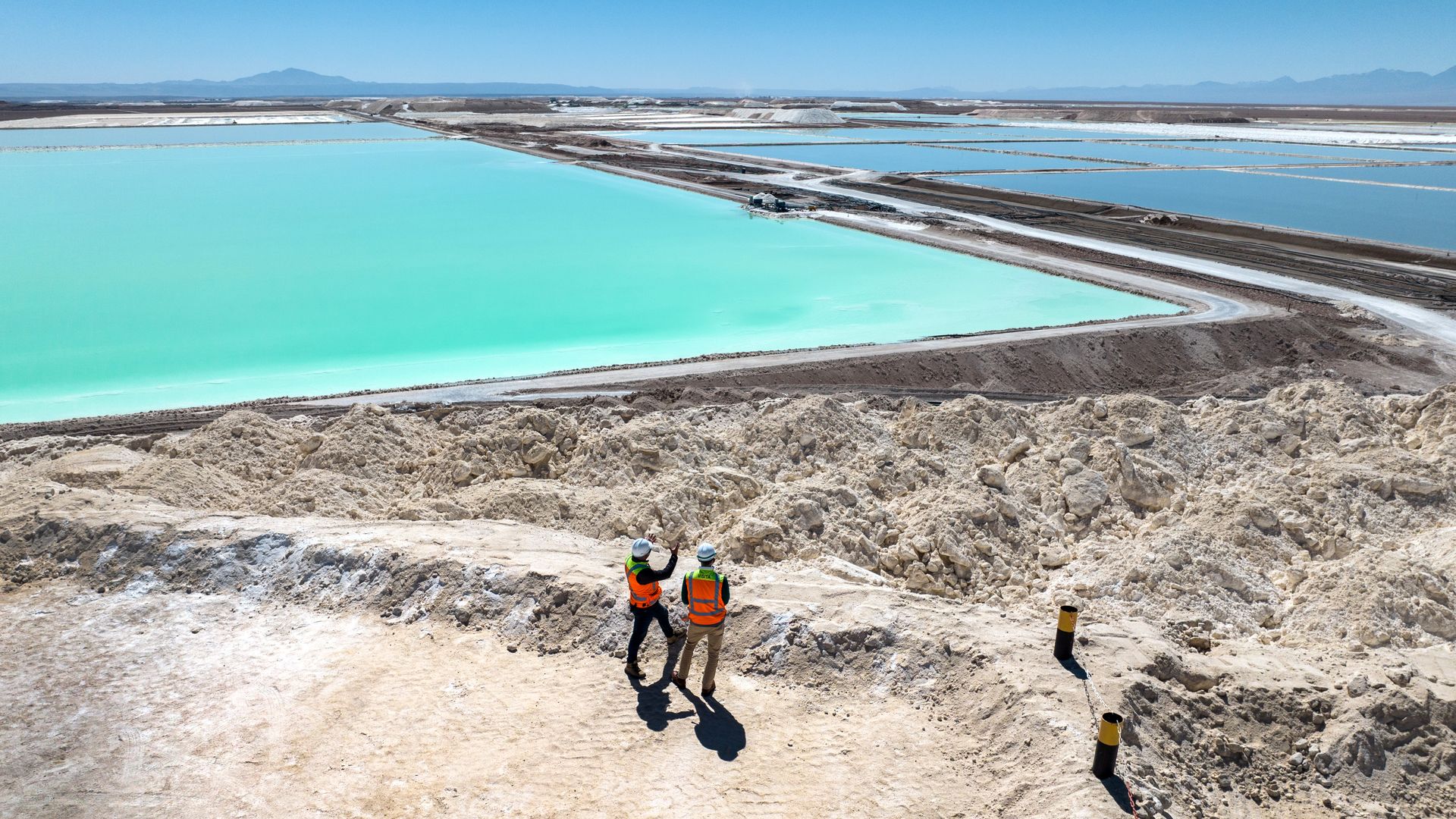 visitors stand atop a large mound of salt bi-product from lithium production at a lithium mine in the Atacama Desert on August 24, 2022 in Salar de Atacama, Chile.