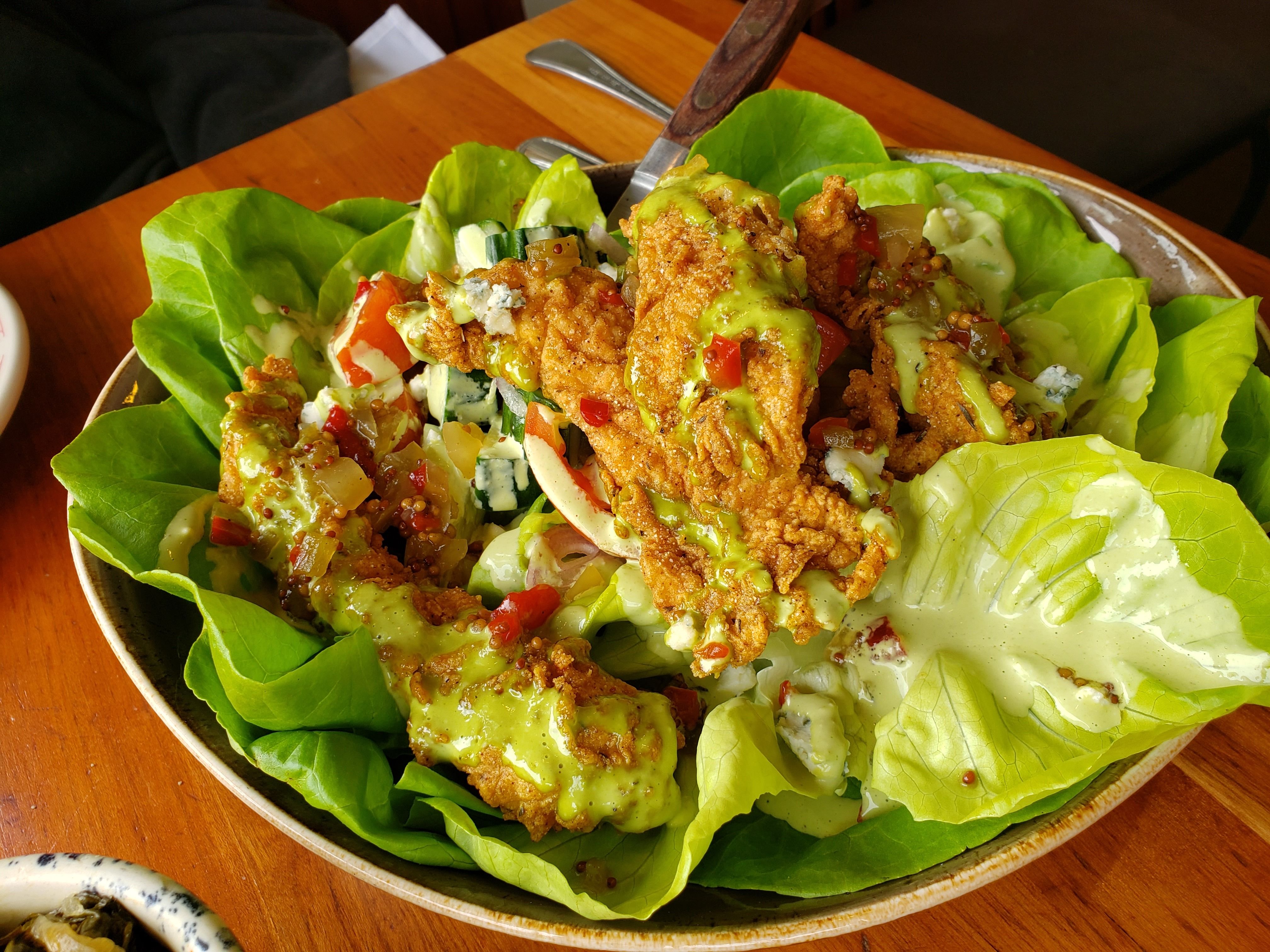 Butter lettuce salad with fried chicken on top.
