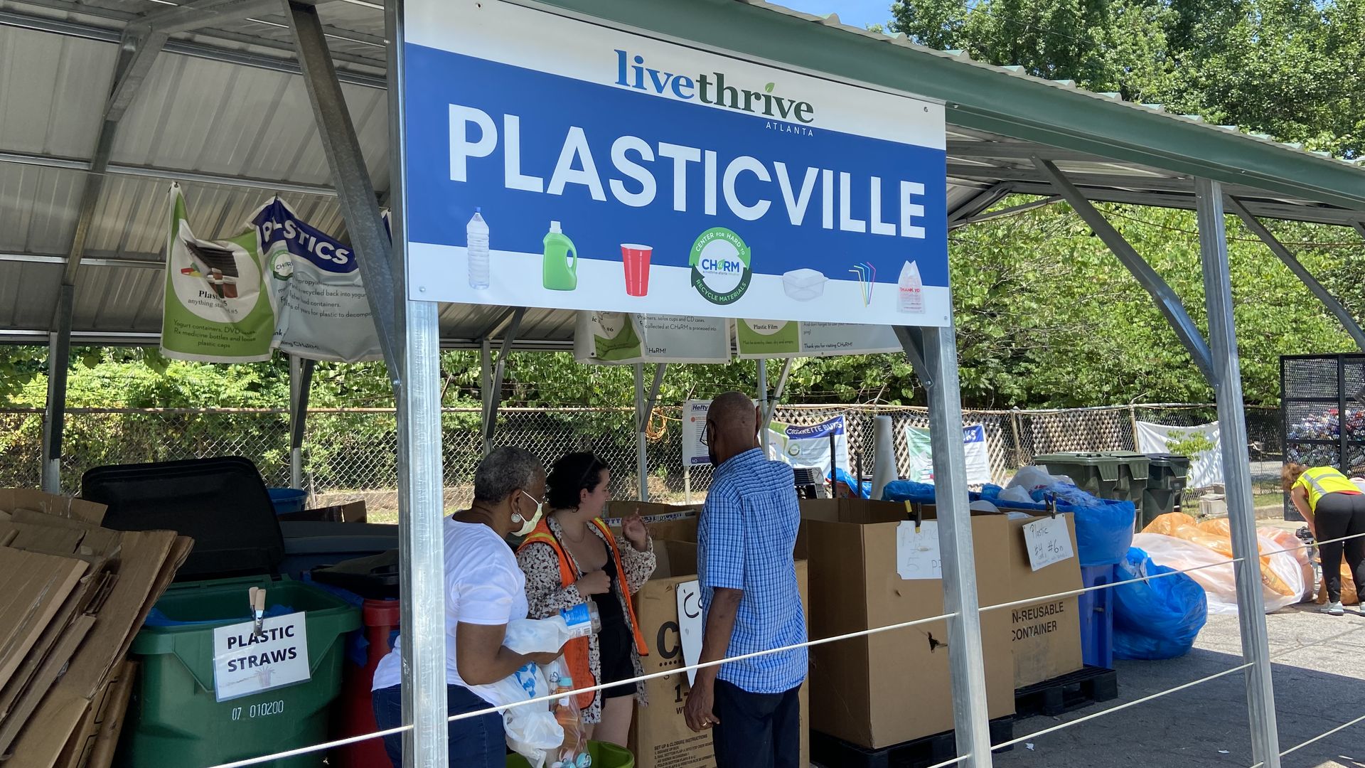 People throw out plastic under a sign that says “Plasticville” at the Center for Hard to Recycle Materials