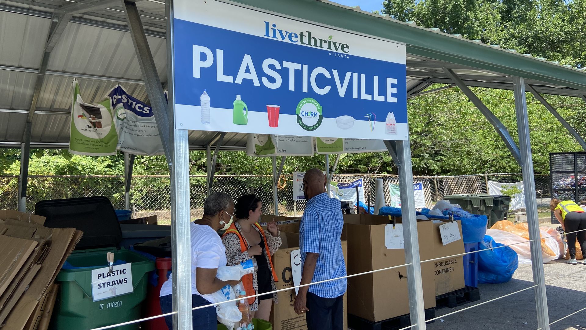 People throw out plastic under a sign that says โPlasticvilleโ at the Center for Hard to Recycle Materials