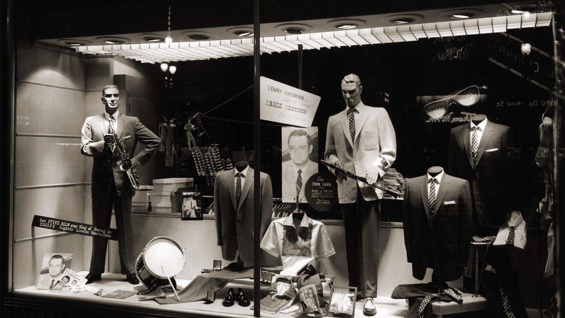 A black and white photo of a shop window at Rubensteins. Men's clothing and mannequins are in the window.