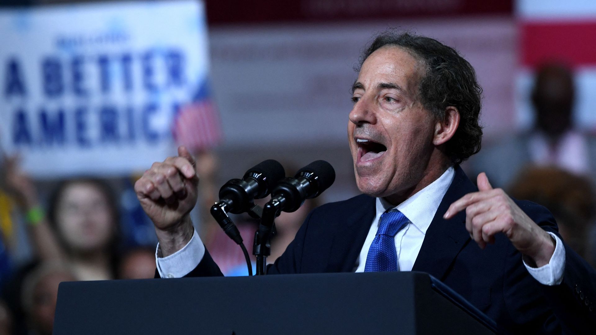 Rep. Jamie Raskin, wearing a dark blue suit, white shirt and blue tie, speaks at a podium during a Biden rally.