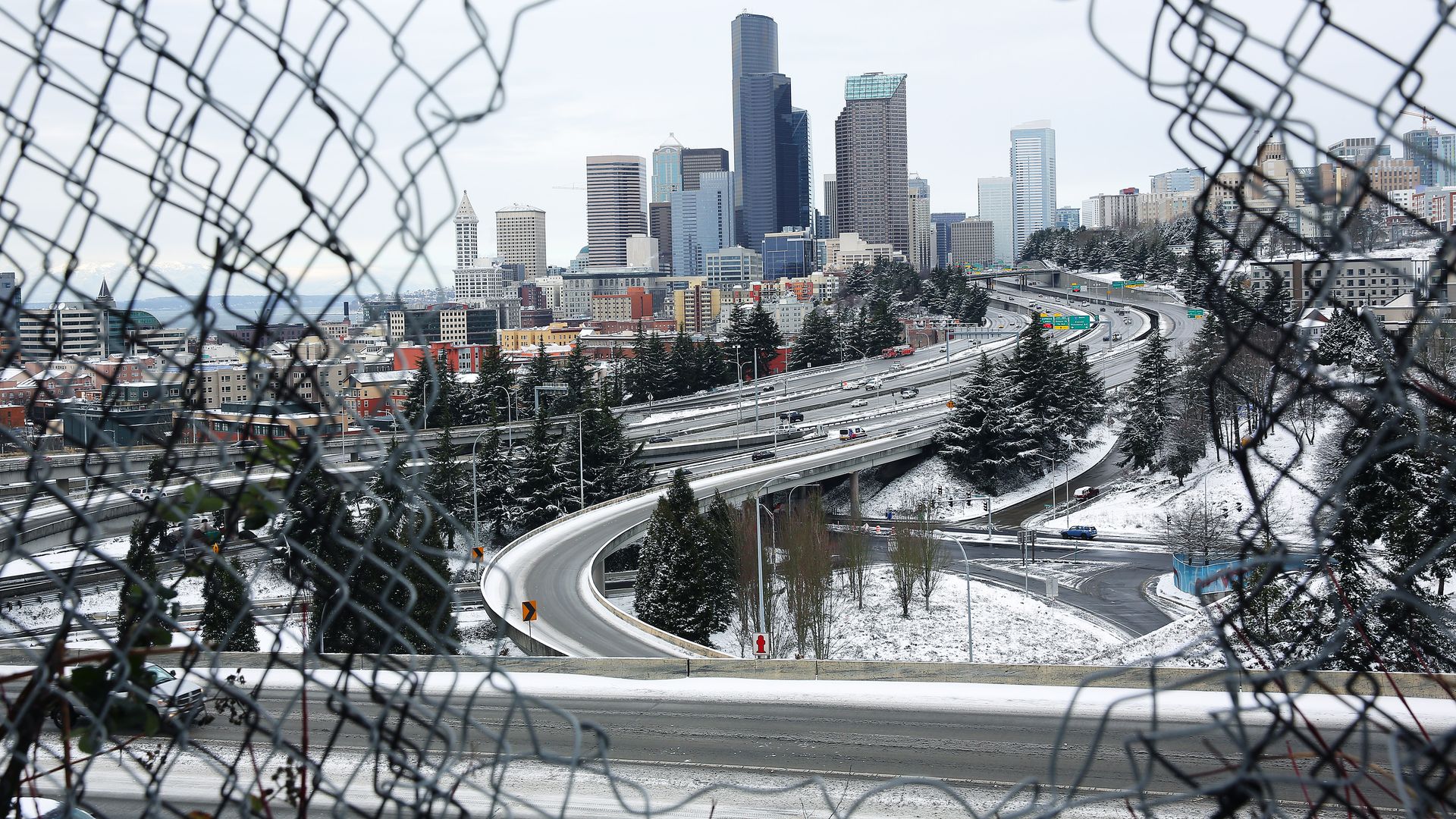 Light snow covers Seattle as seen through a chainlink fence