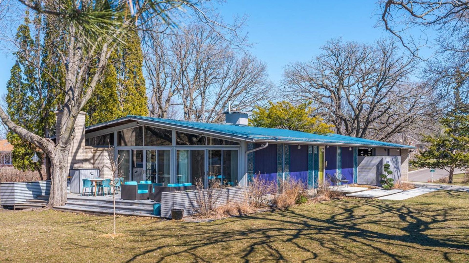 A mid-century modern home with a blue roof and purple siding. 