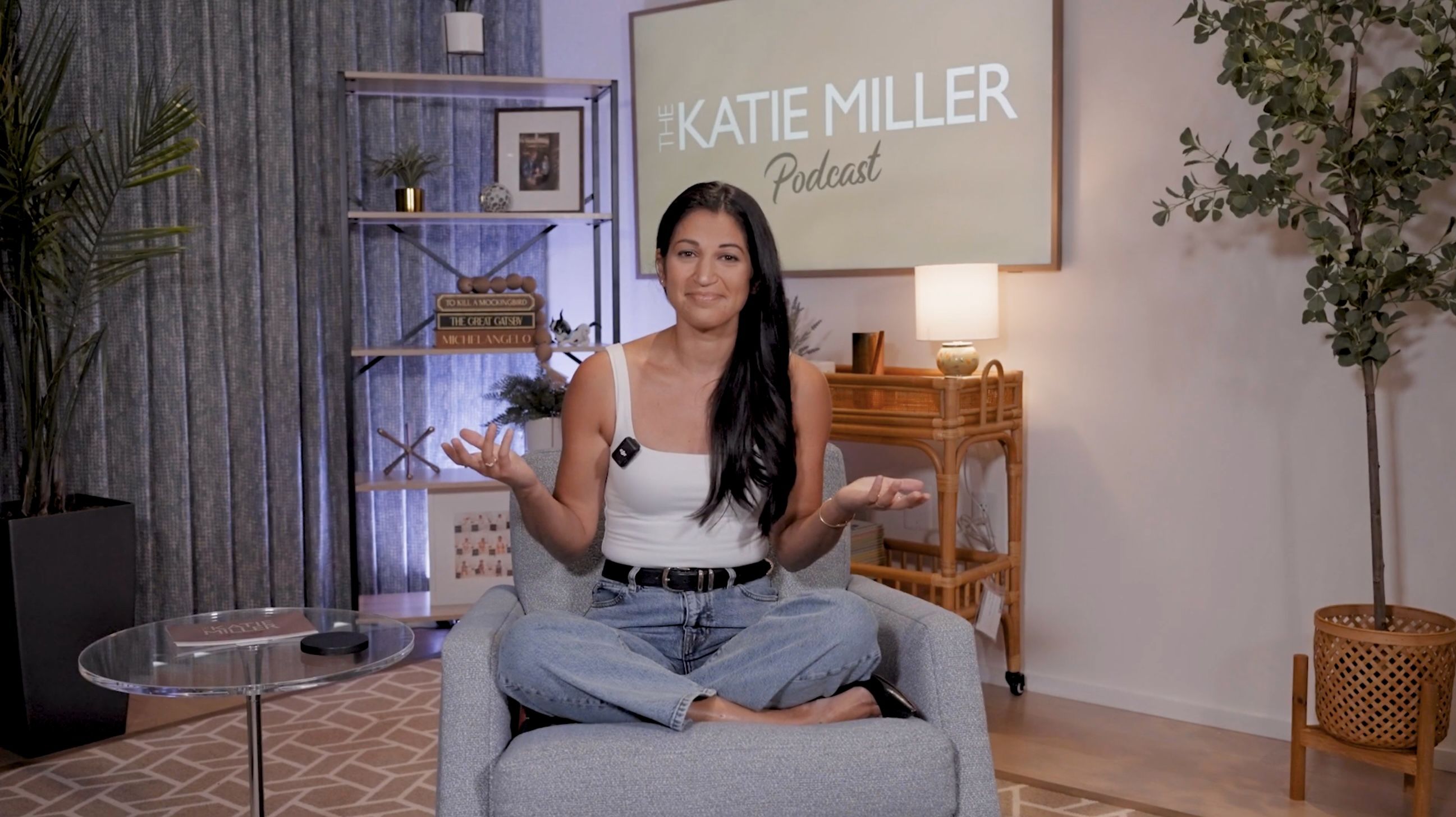Katie Miller poses with a screen showing "The Katie Miller Podcast" in the background.