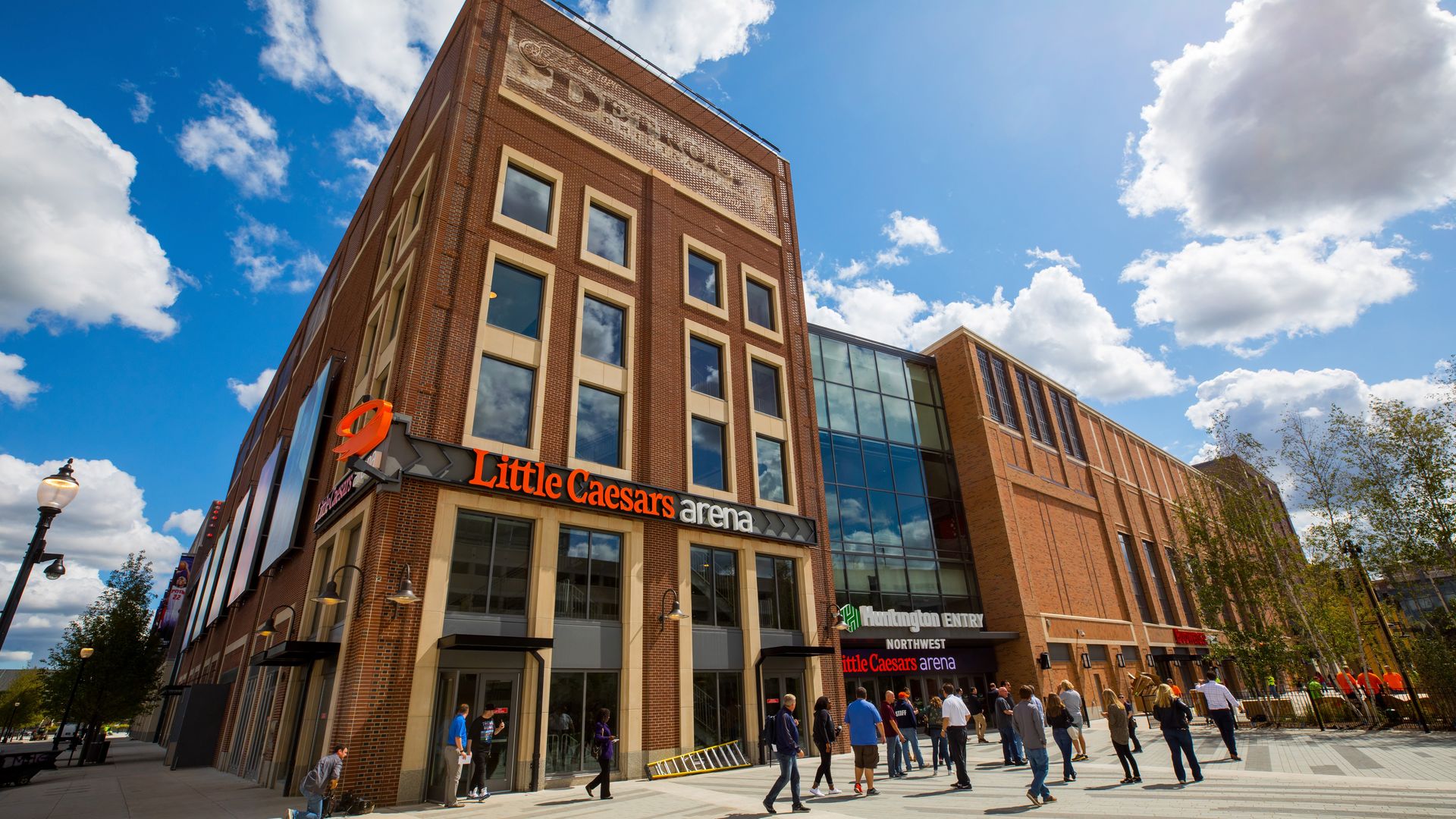 The exterior of little caesars arena, with a big sign