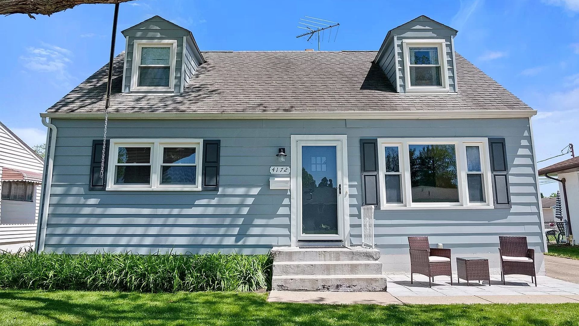 T he facade of a small house with chairs in front. 