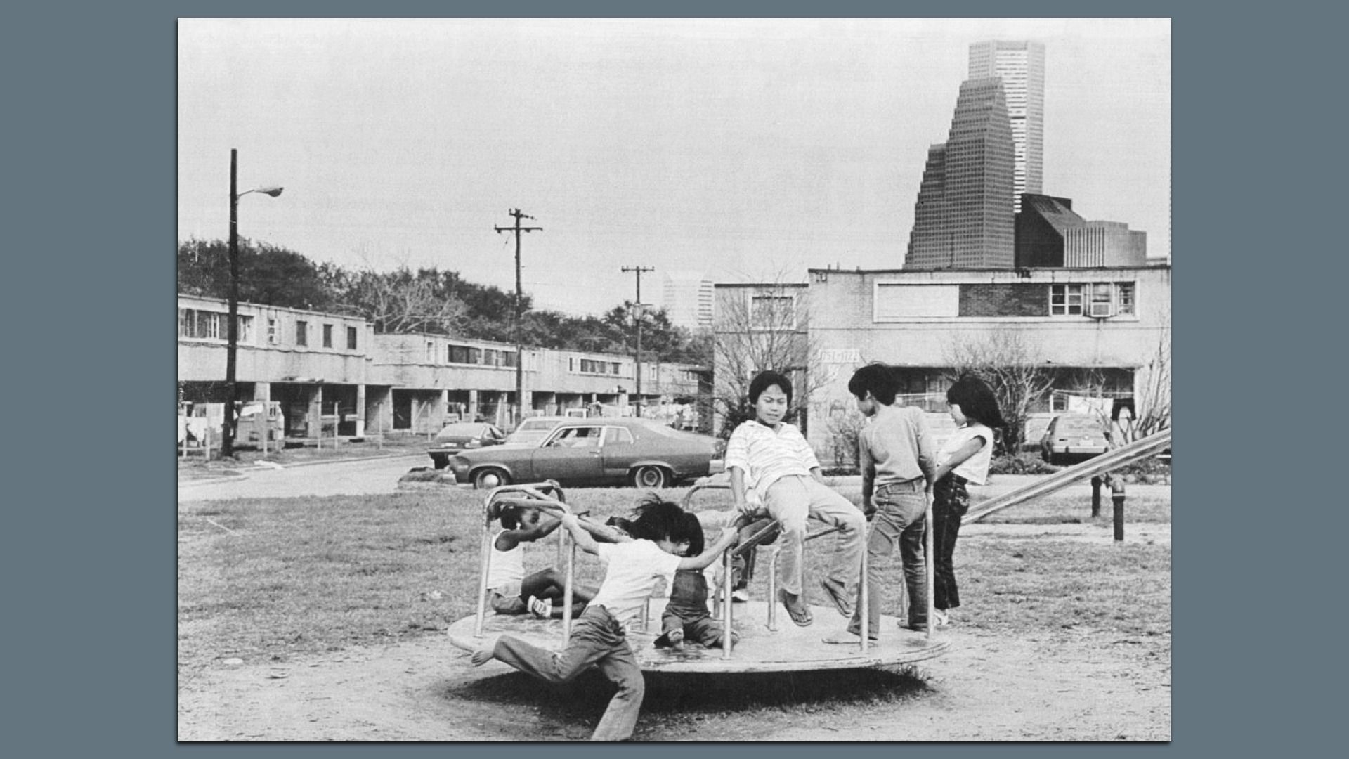 Vietnamese children play on playground at the Allen Harway apartments two story building in background. The apartments are on the edge of downtown Houston, Texas, March 18, 1985.