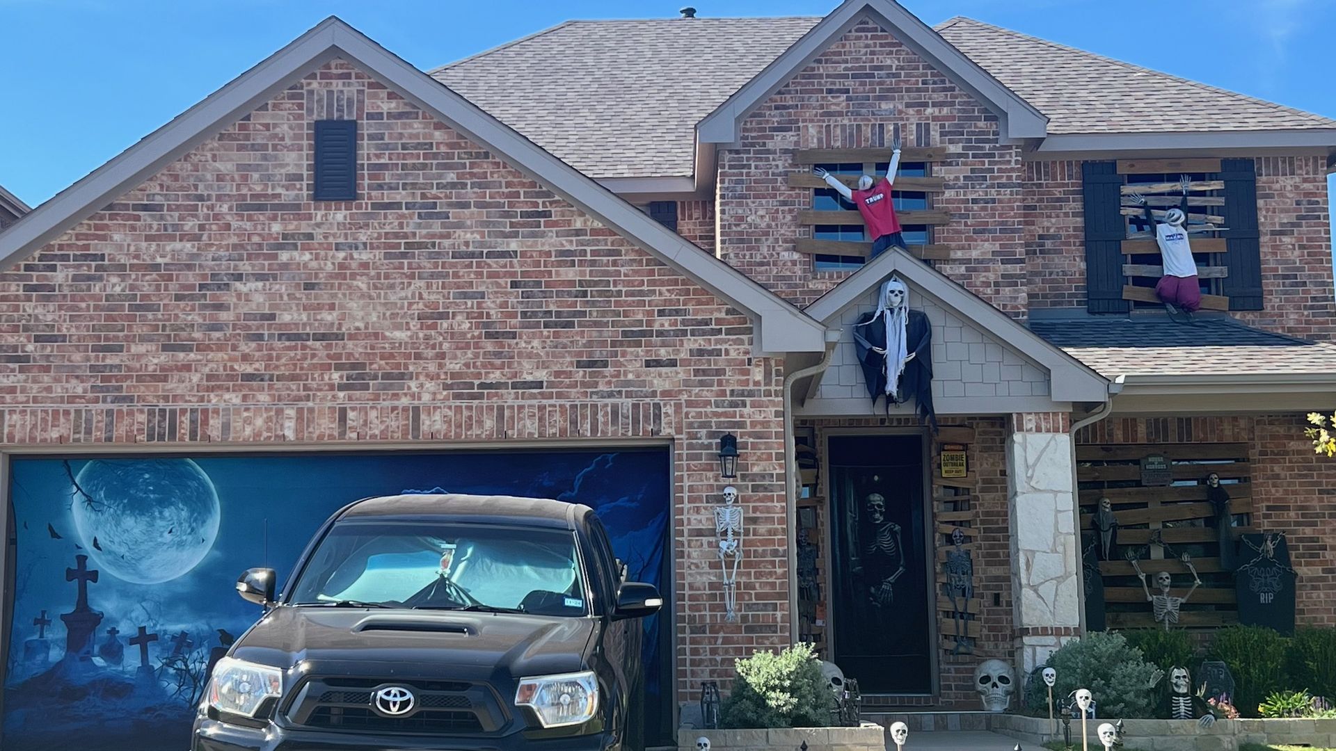 A house with Halloween decor outside, from a garage wrap to ghouls dangling from the windows