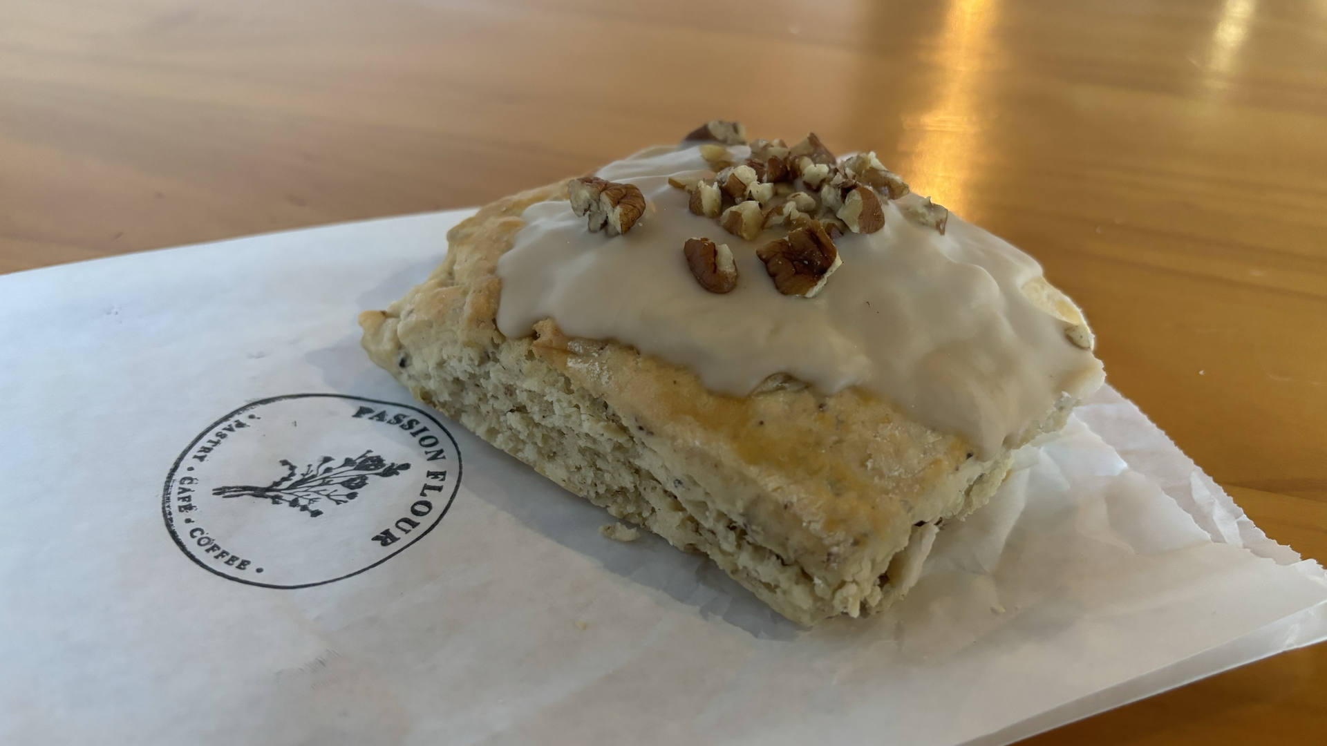 A maple scone with walnuts on top sits on a pastry bag.