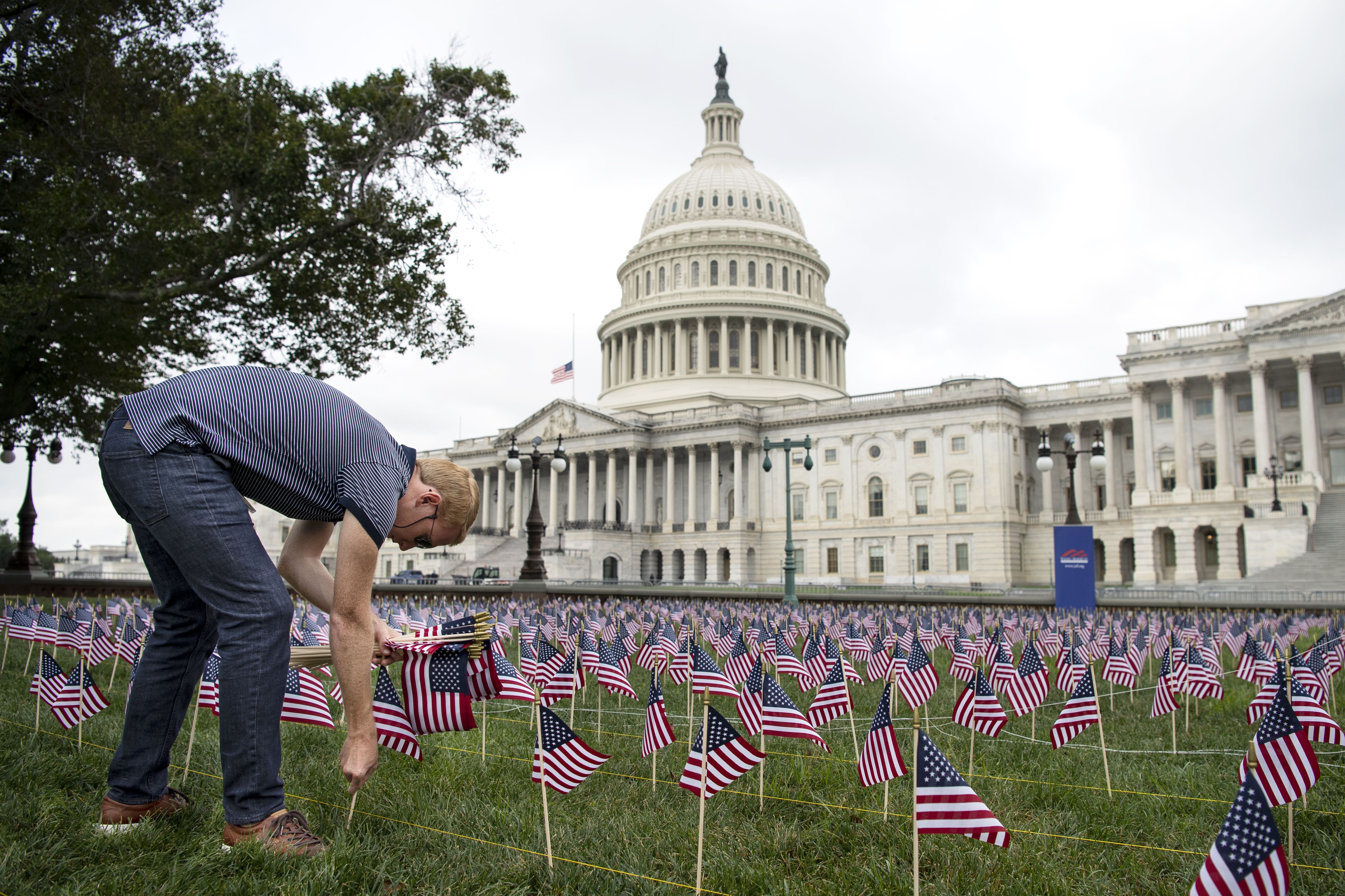 People place American flags to represent the lives lost during the 9/11 attacks, outside of the Capitol.