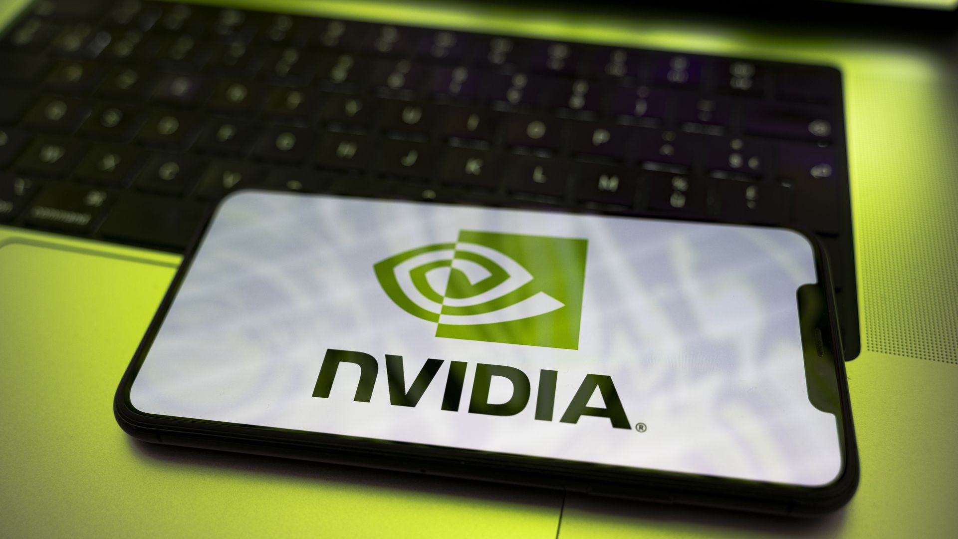 The Nvidia logo appears on a smartphone screen placed on a laptop keyboard. 

