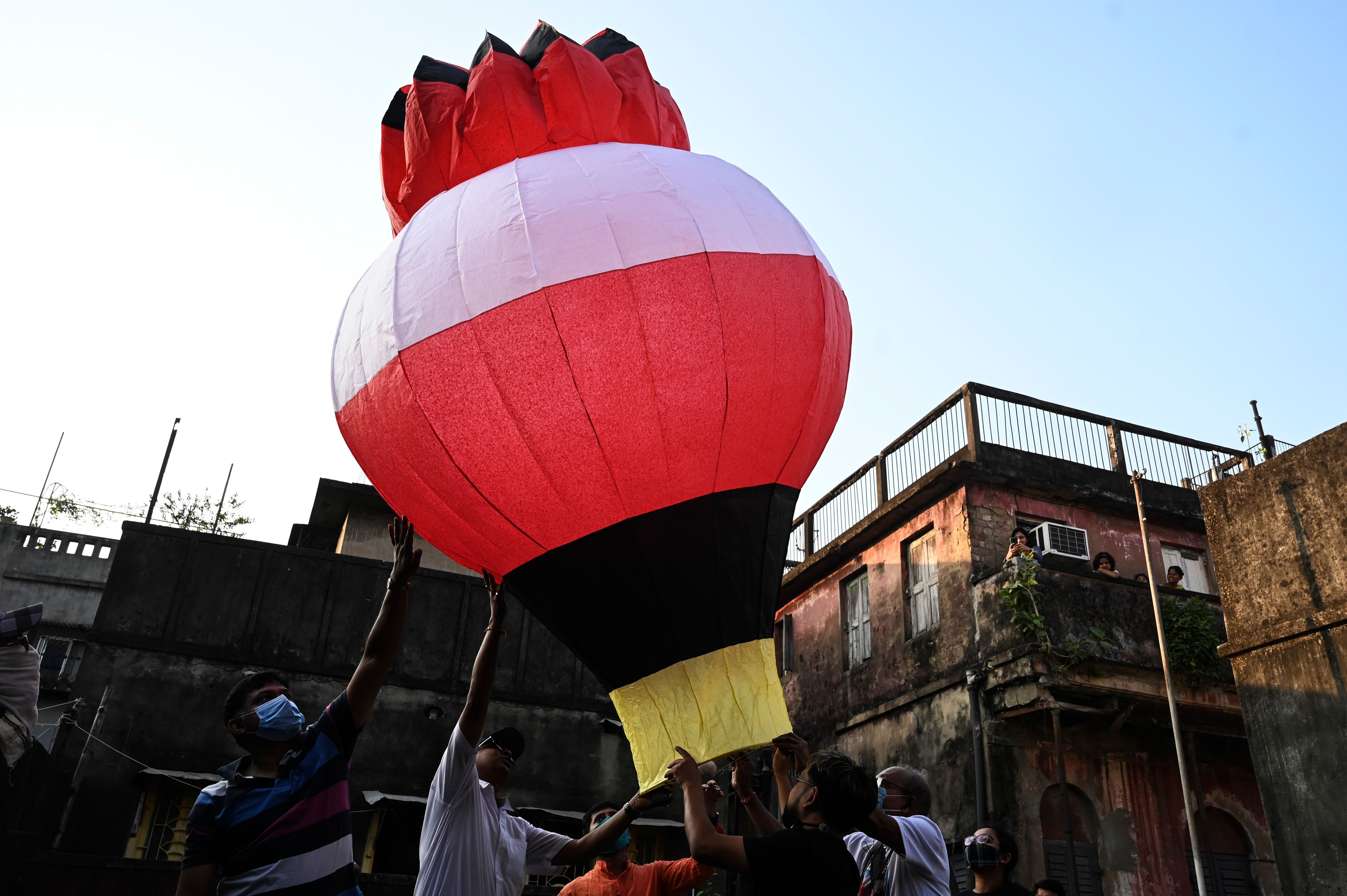 Revelers release a handmade sky-lantern from the terrace of a building to celebrate Diwali in Kolkata